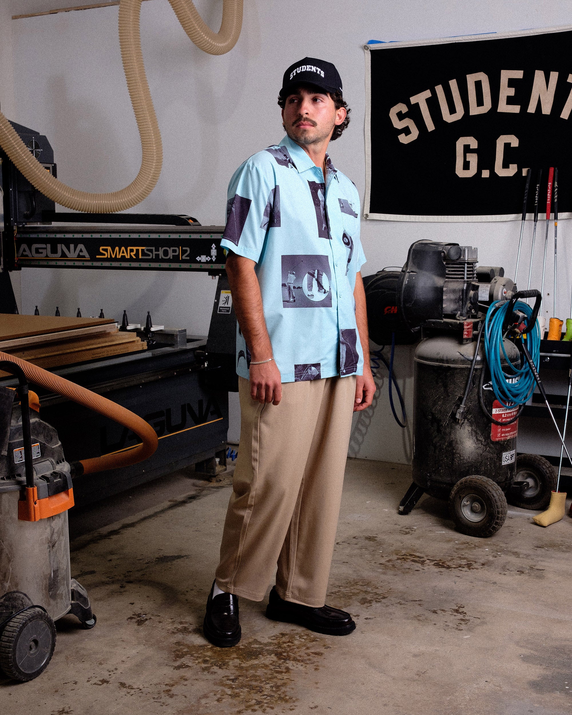Person standing in a workshop with machinery and tools in the background