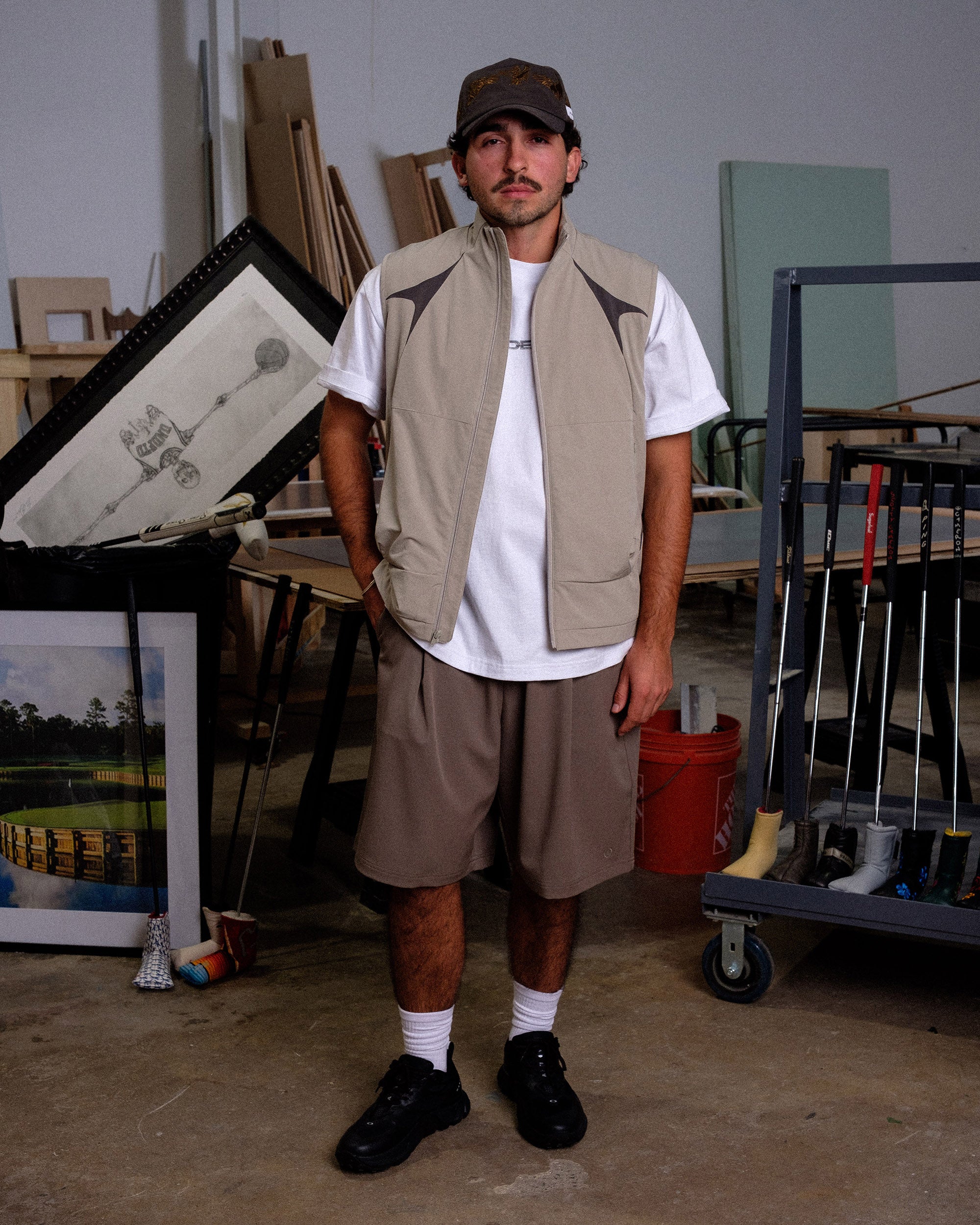 Man standing in a workshop or storage area with tools and materials around