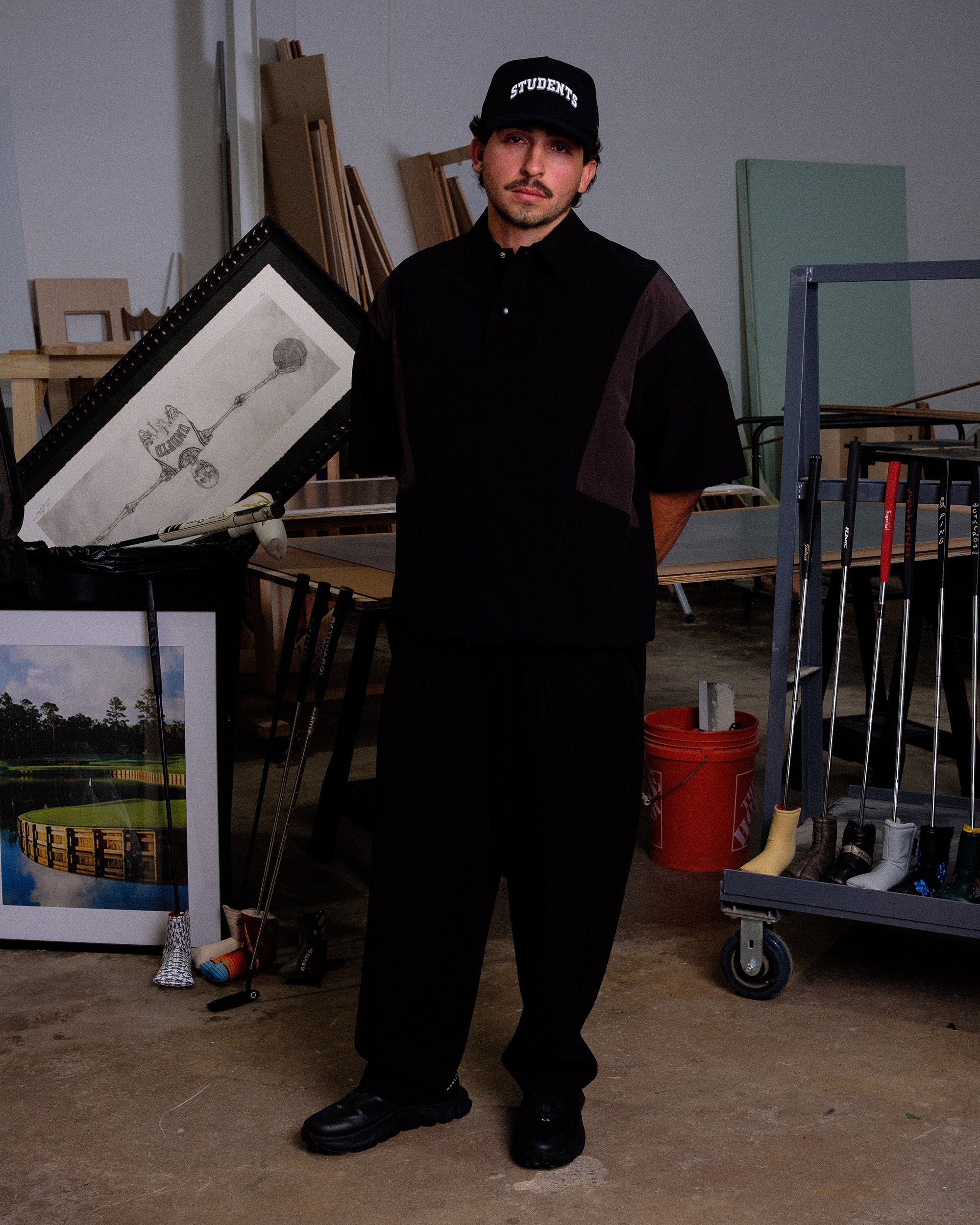 Man holding in an art studio with various artworks and tools in the background.