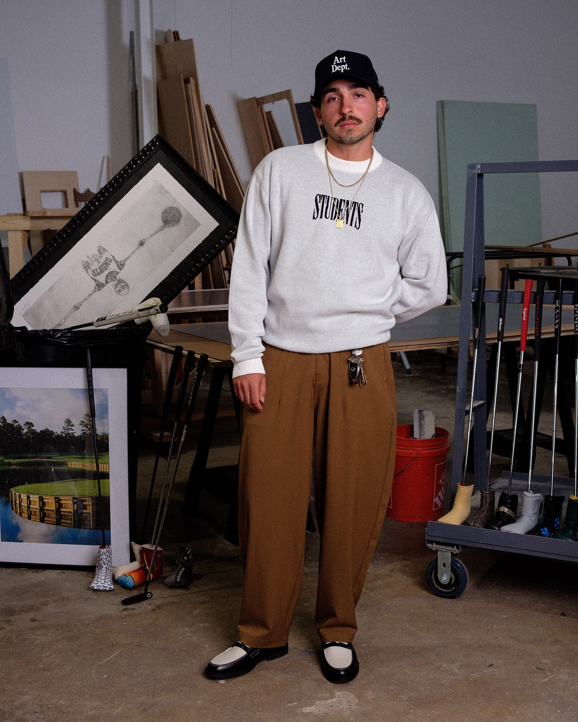 Person wearing a gray sweatshirt with 'STUDENTS' text in an art studio.