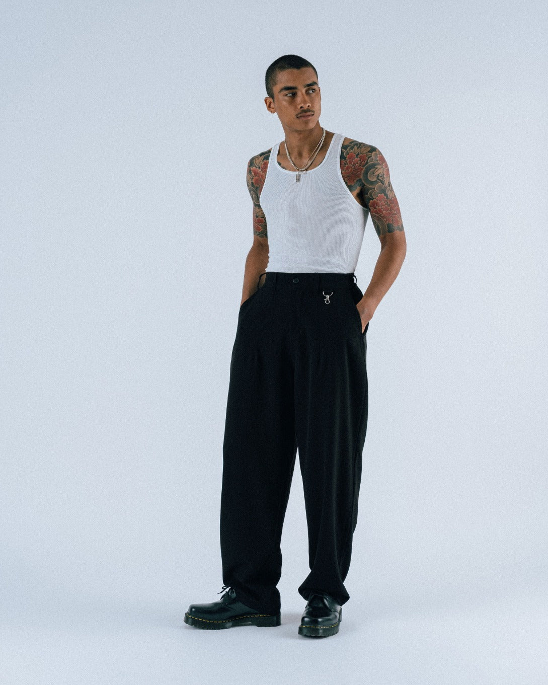 Person wearing a white tank top and black pants on a white background