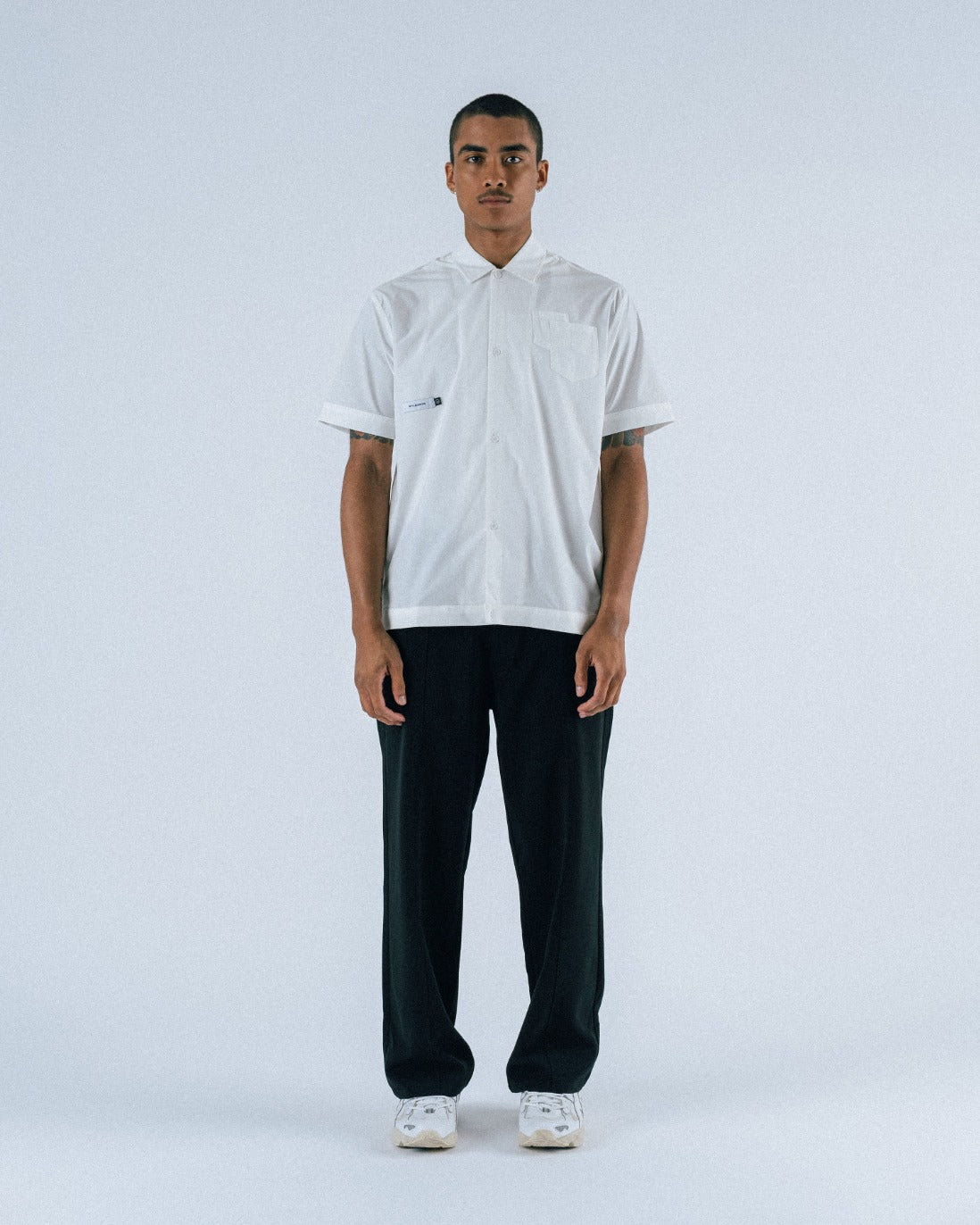 Person wearing a white shirt and black pants on a light gray background