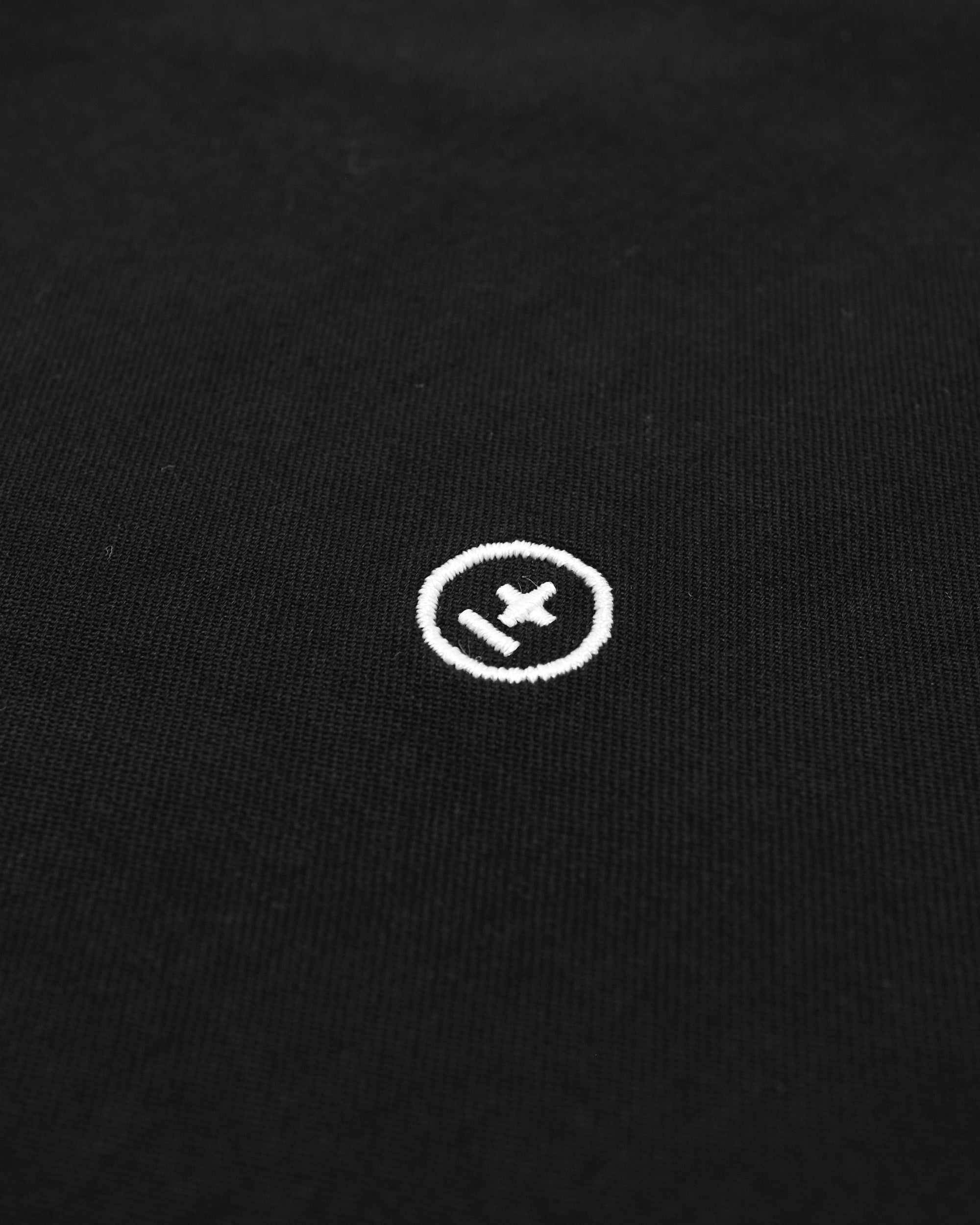 Close-up of a black garment with a white logo on a black background