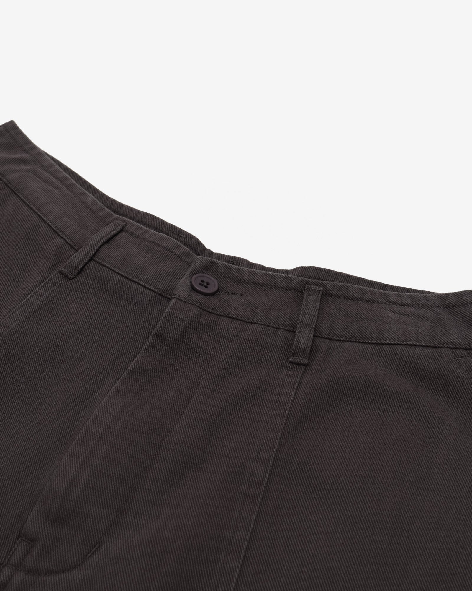 Close-up of dark brown pants with a button on a white background