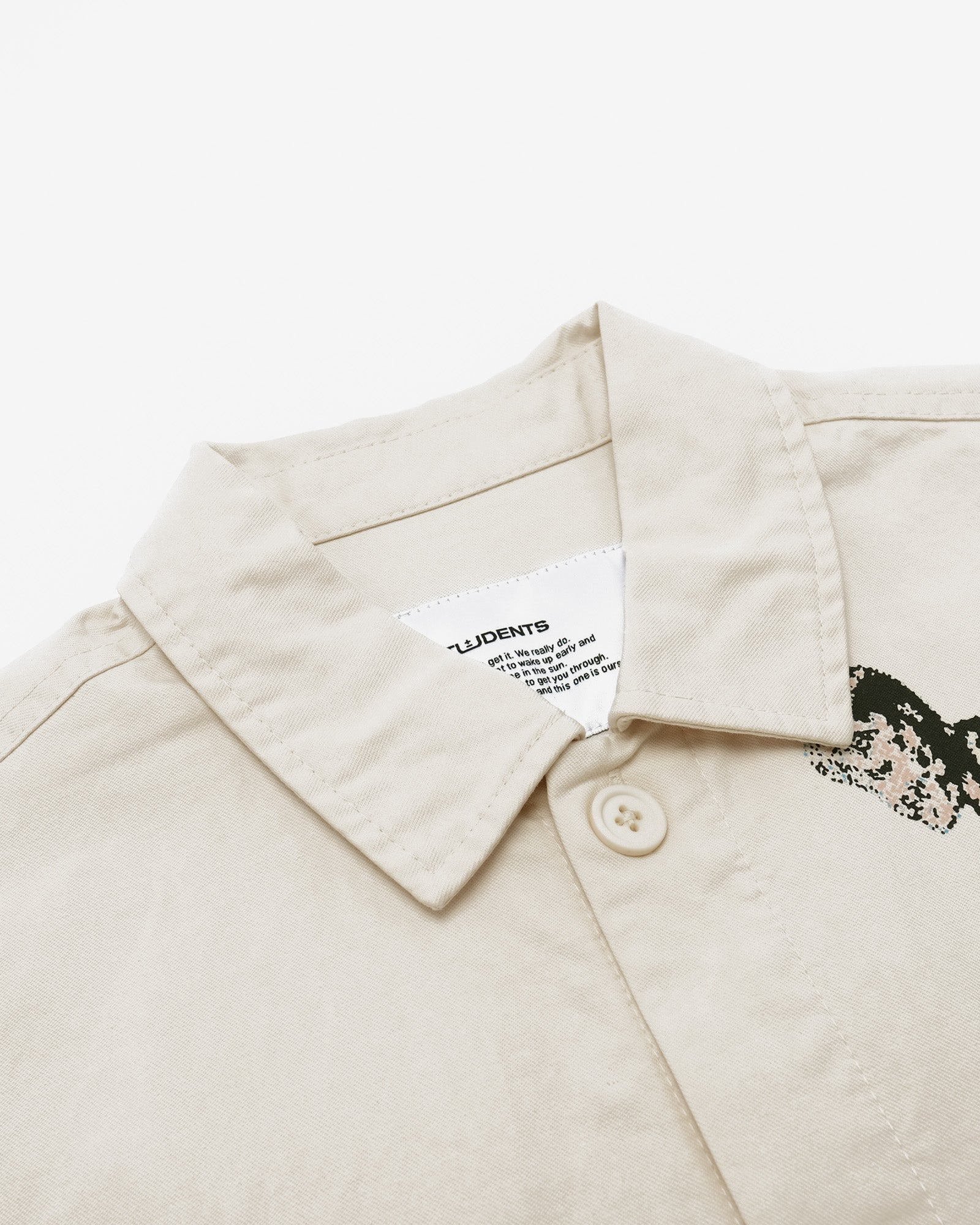 Close-up of a beige jacket with a label on the collar against a white background