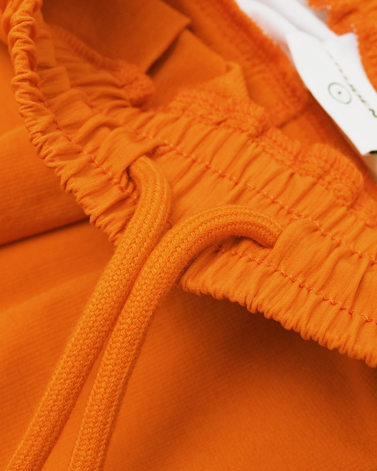Close-up of an orange apparel with a brand tag.
