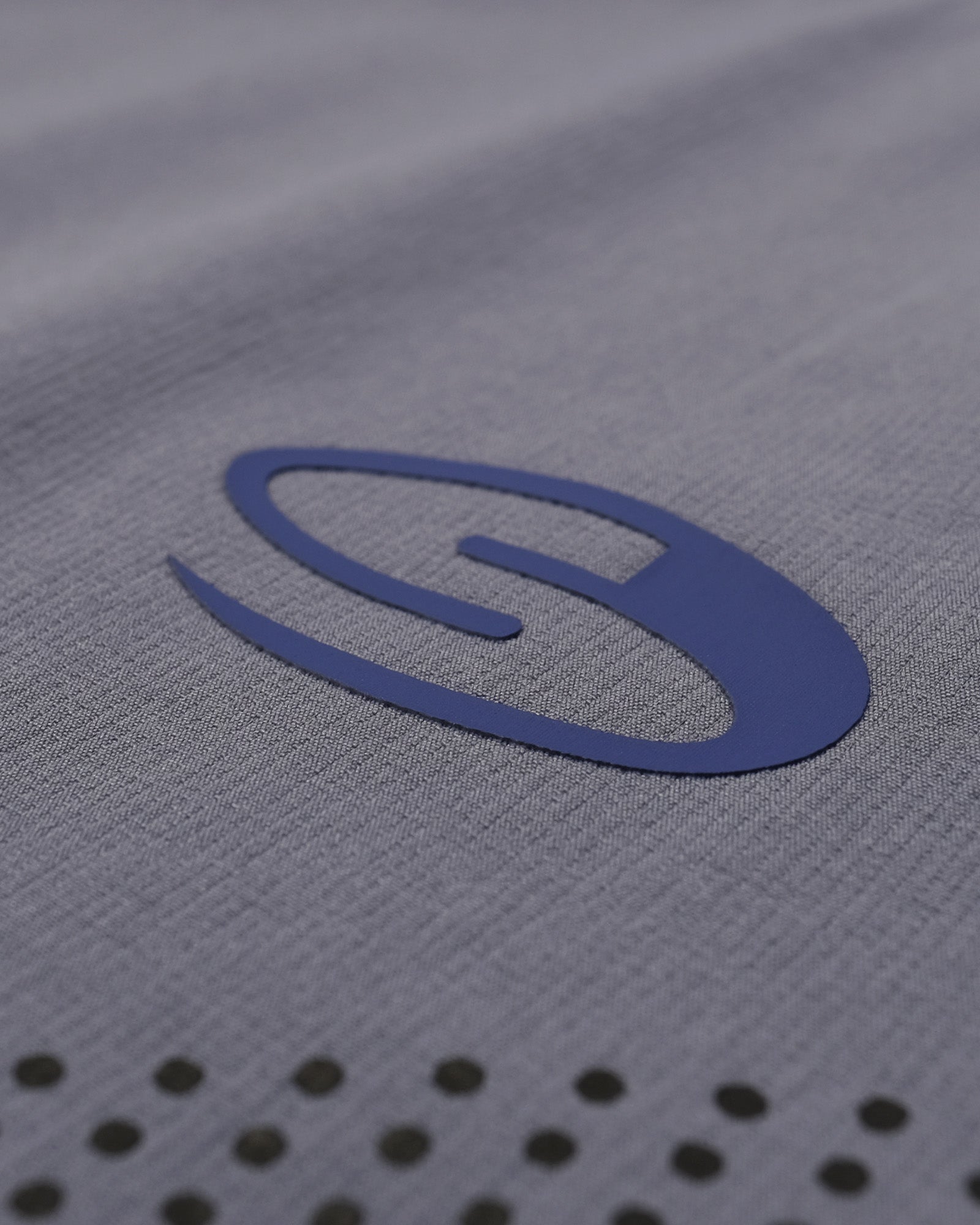 Close-up of a gray fabric surface with a blue logo and black circular patterns.