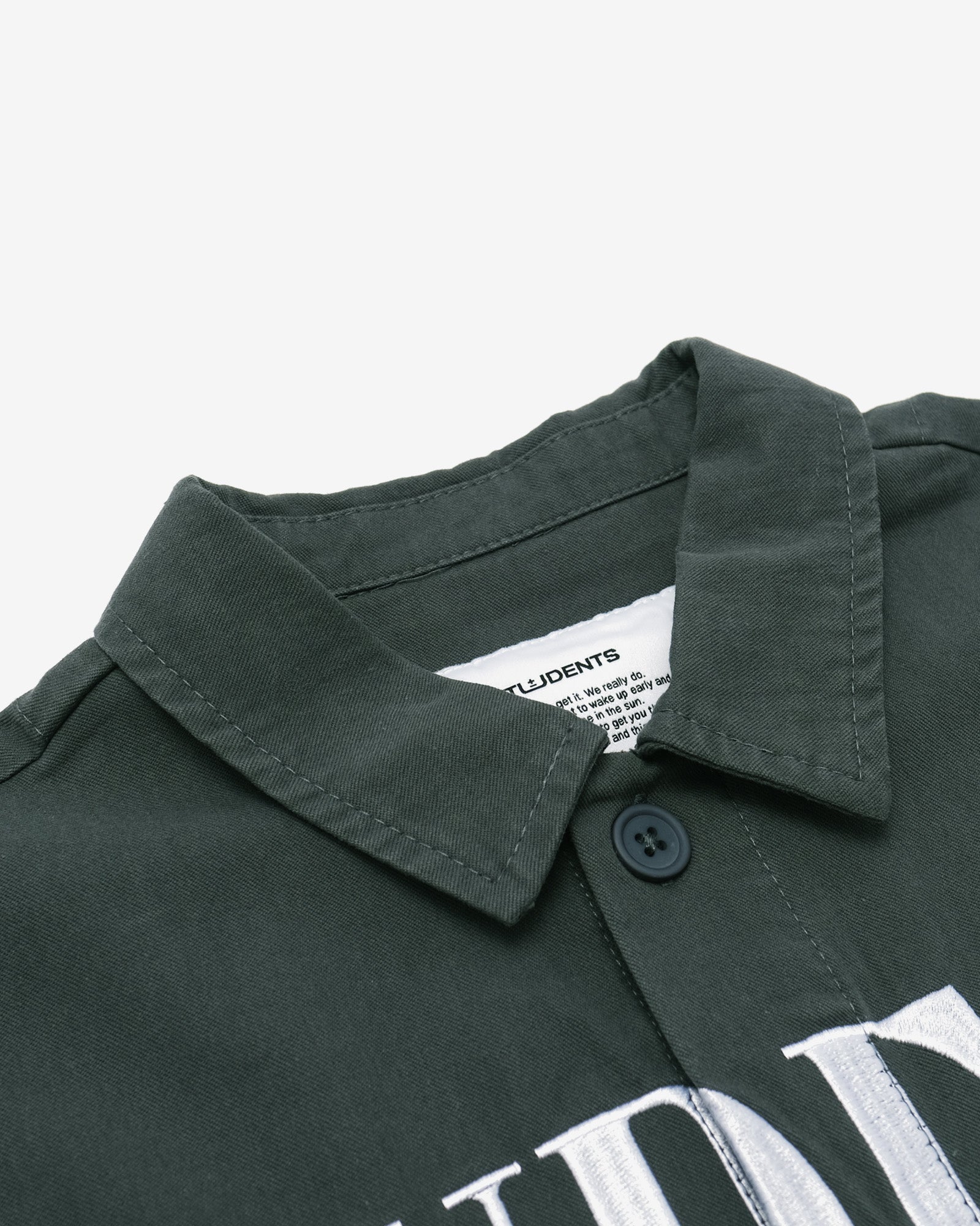 Close-up of a dark green shirt collar with a button on a light gray background