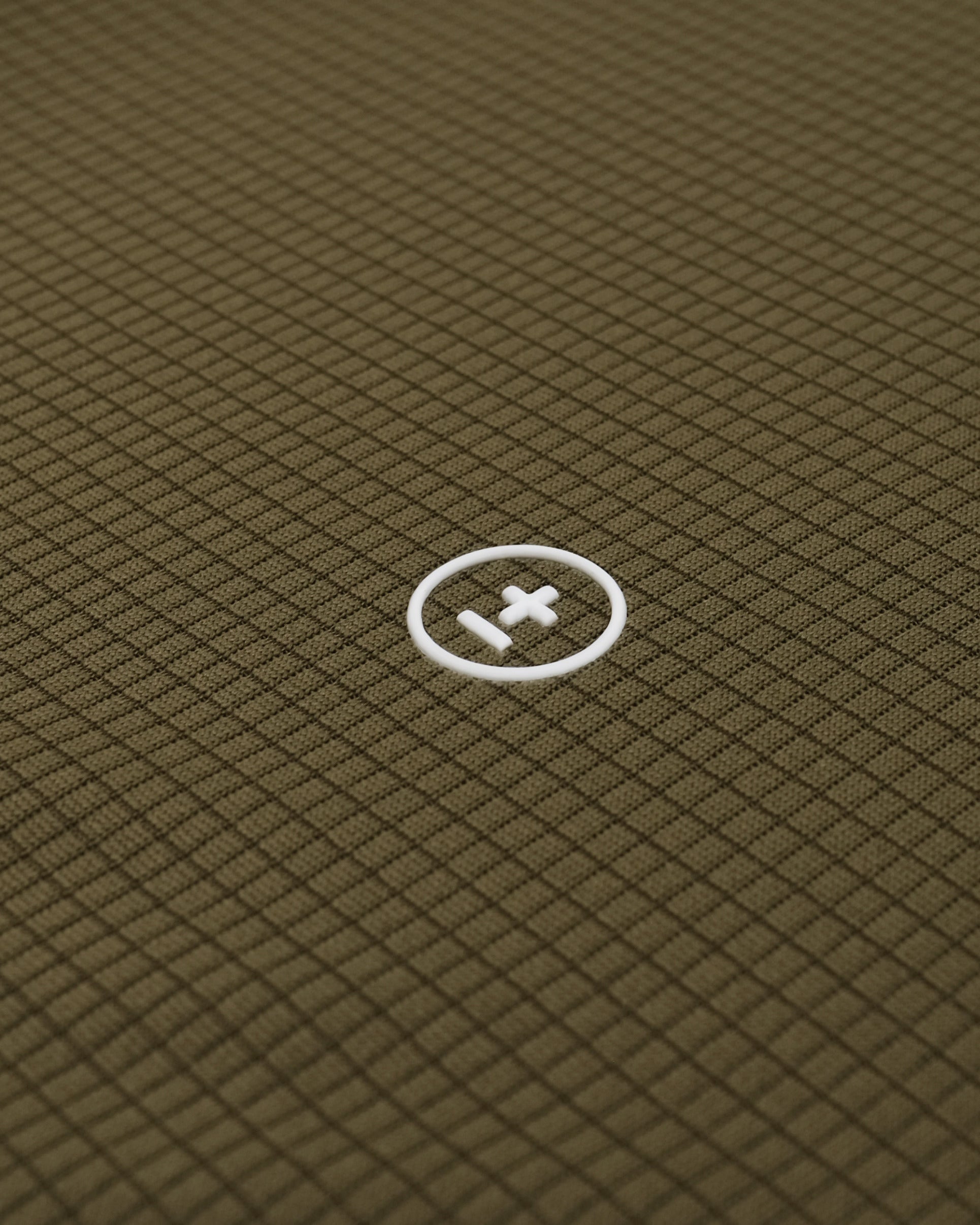 Close-up of a textured green fabric with a white logo in the center.