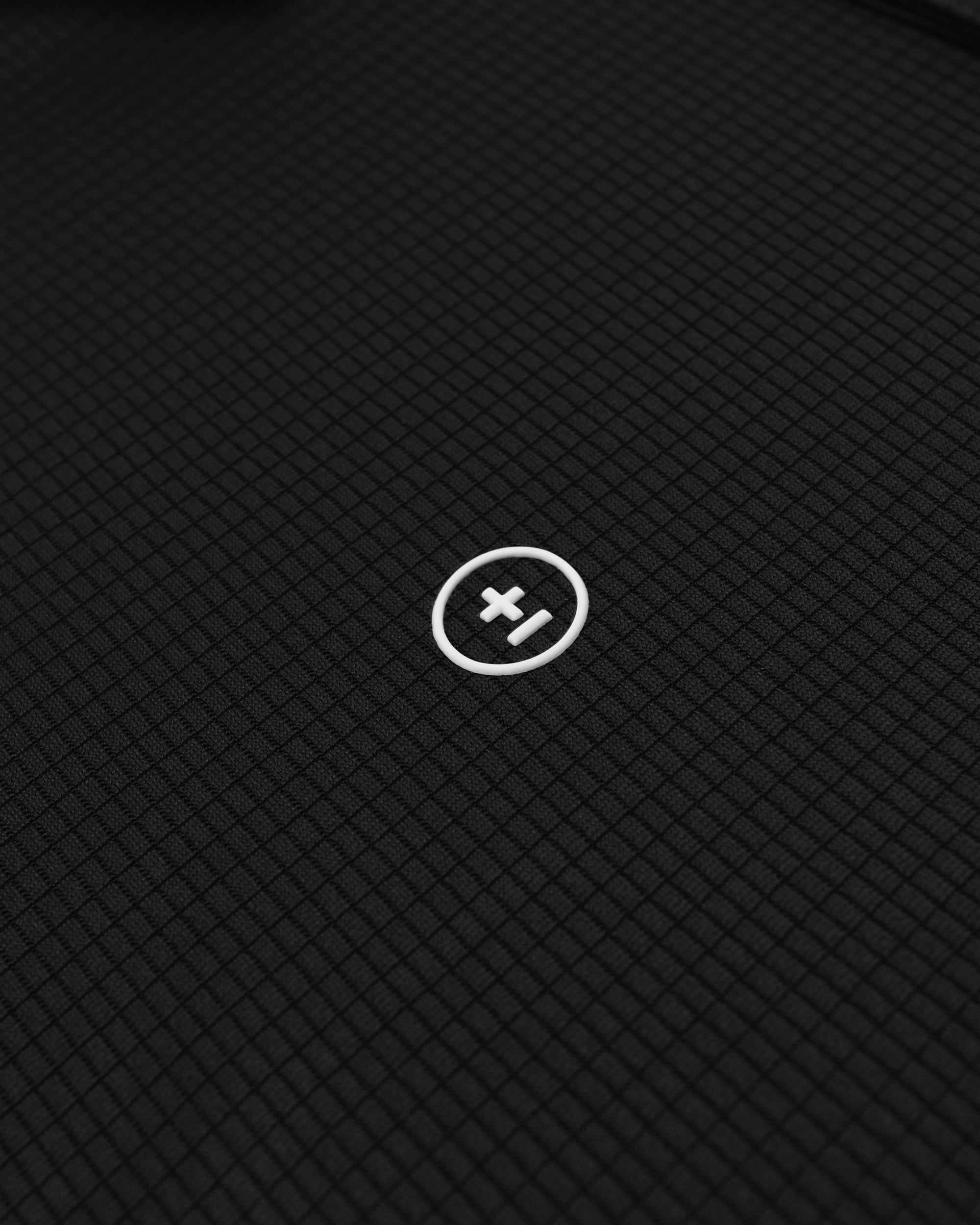 Close-up of a textured black surface with a white logo in the center.