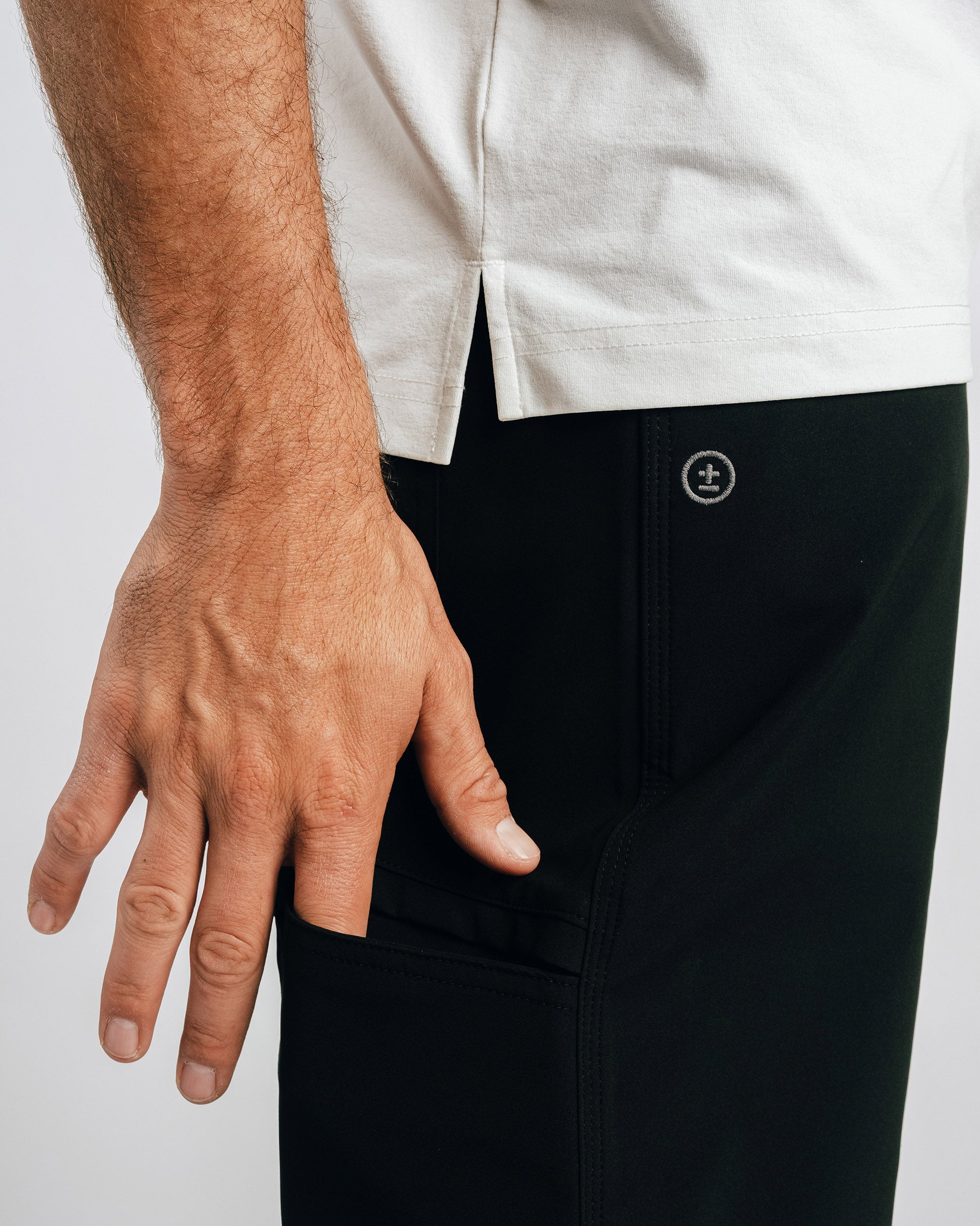 Person wearing black pants with a brand logo on a light gray background