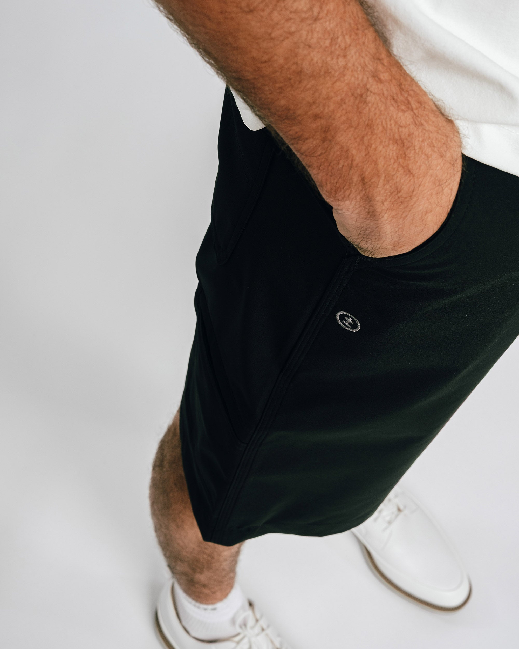 Person wearing black shorts with a brand logo on a white background