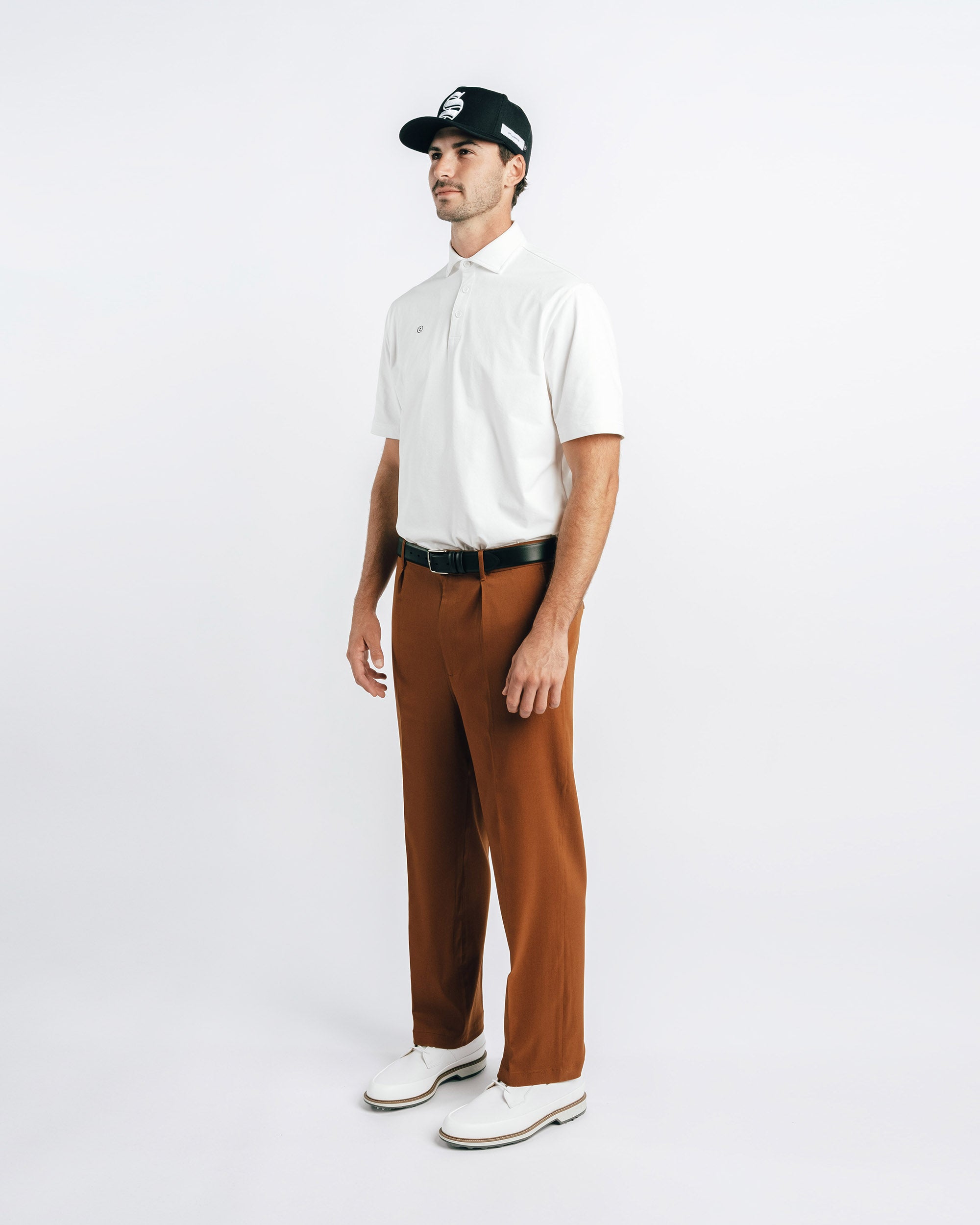 Man wearing a white shirt, brown pants, and a black cap on a white background