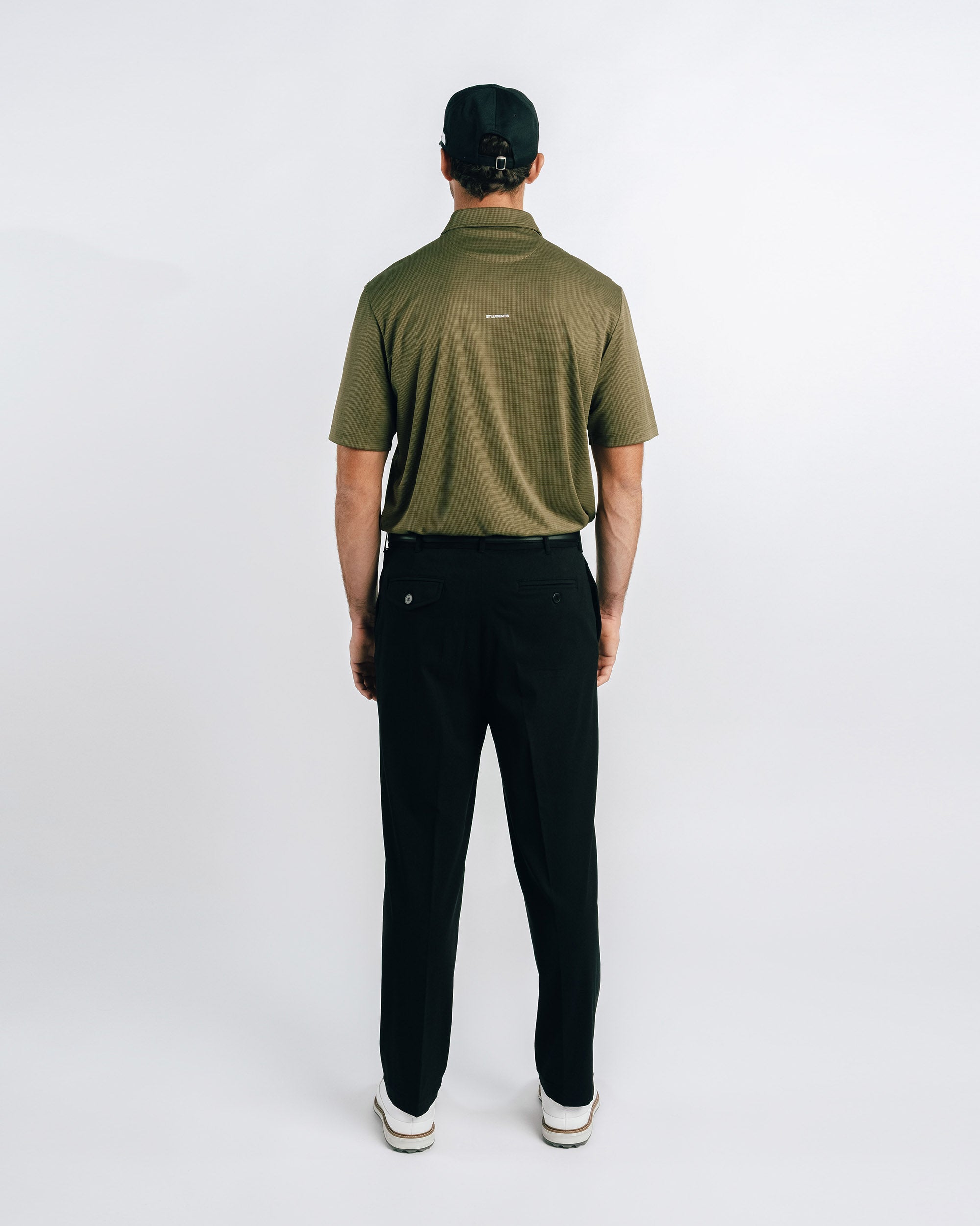 Man wearing a green polo shirt and black pants on a white background