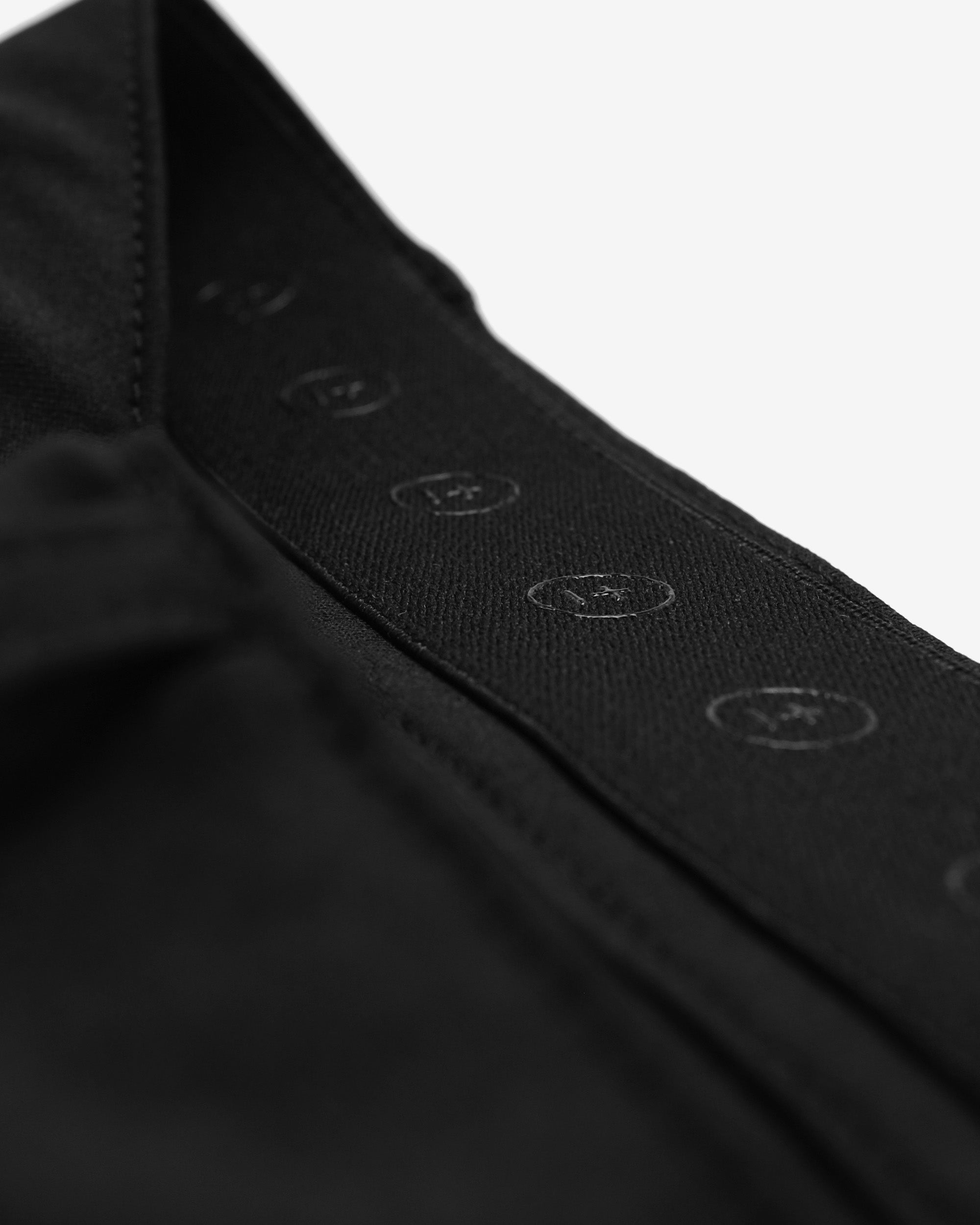 Close-up of a black shirt with button details on a white background