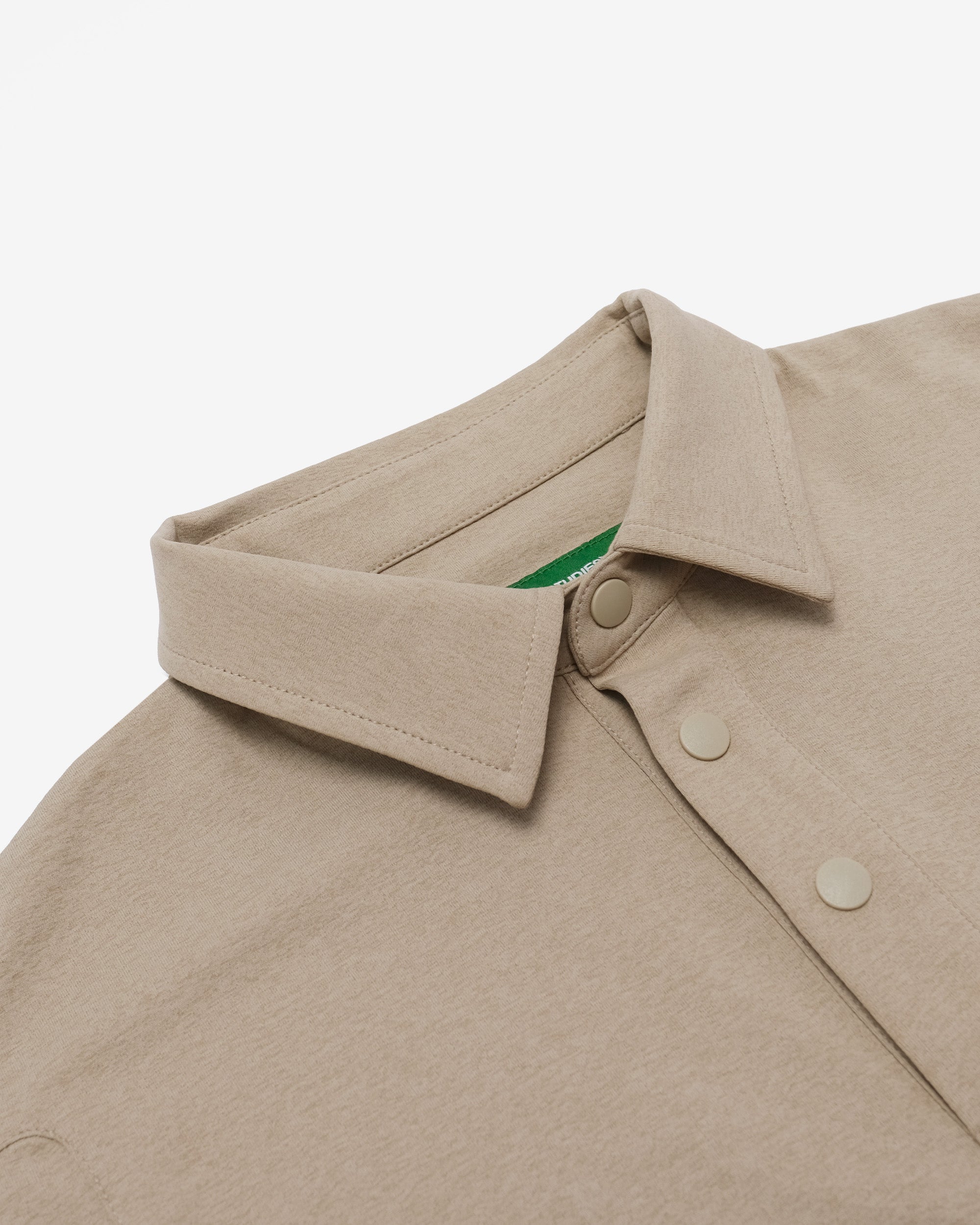 Close-up of a beige jacket collar with a brand logo on a white background