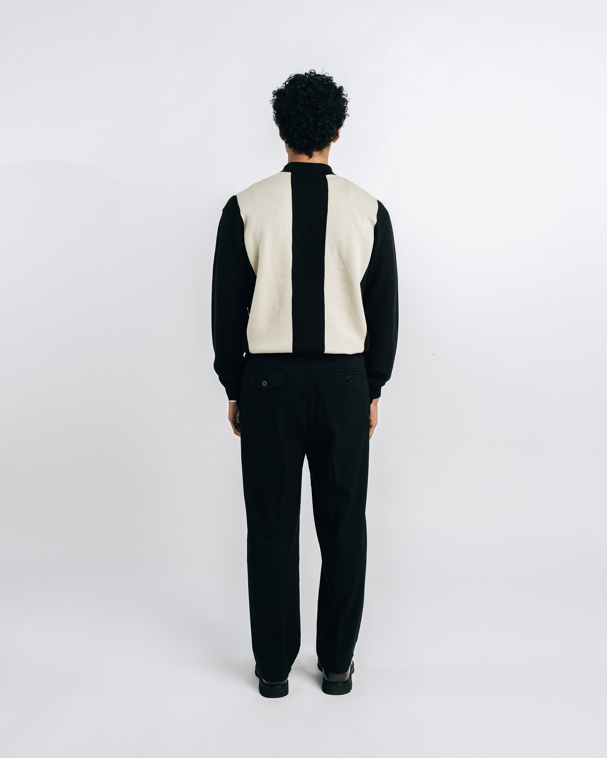 Man wearing a black suit with a white vest on a white background