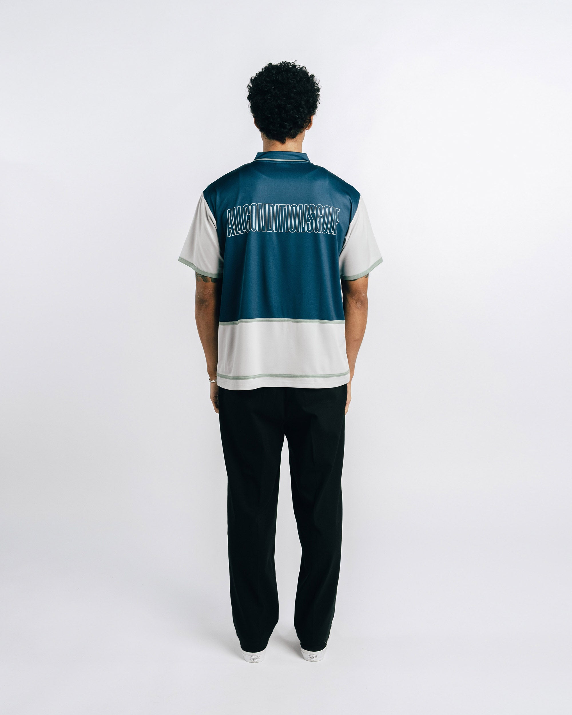 Person wearing a two-tone jacket with text on the back against a white background