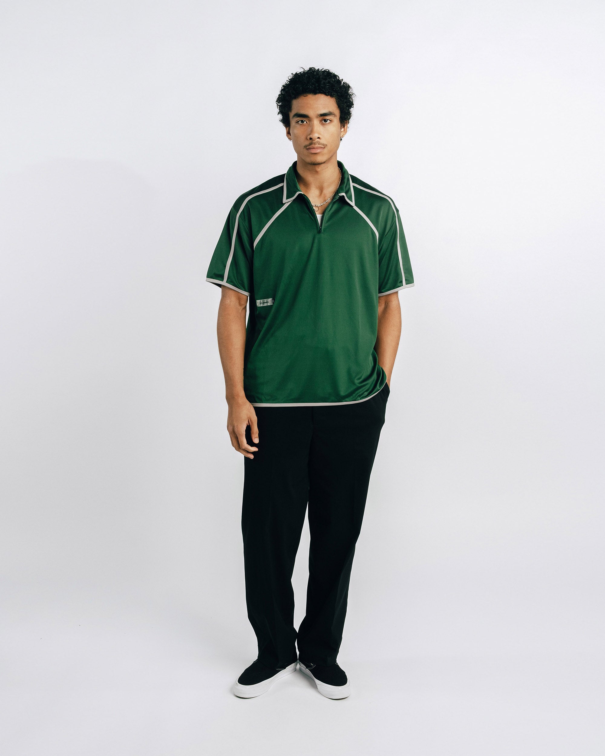Man wearing a green polo shirt with white accents on a white background