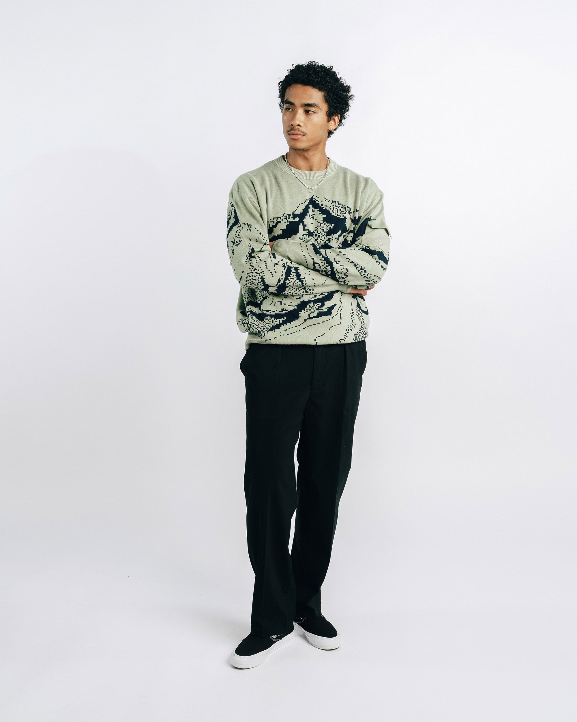 Green sweater with black mountain design on a white background