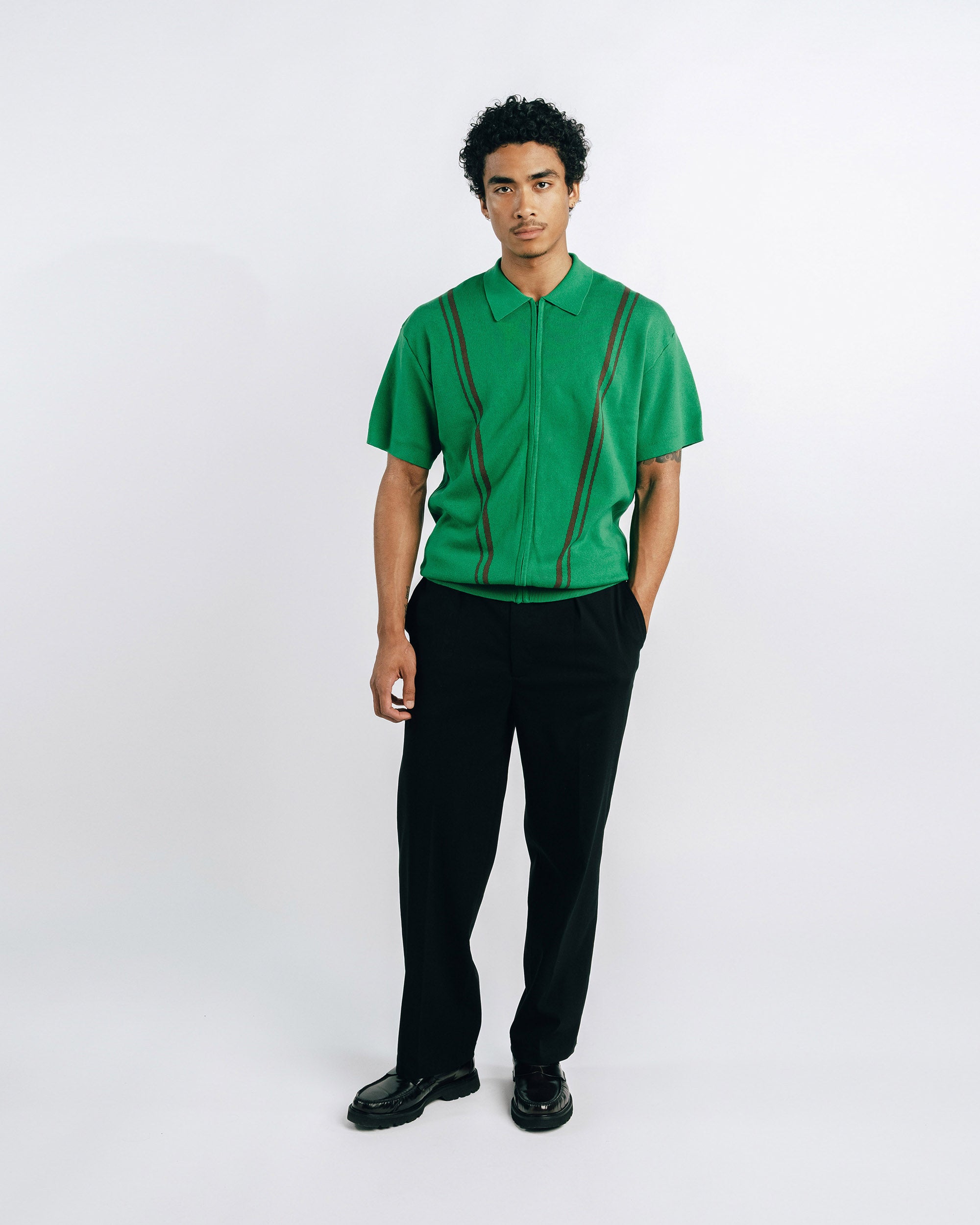 Person wearing a green shirt with suspenders on a white background