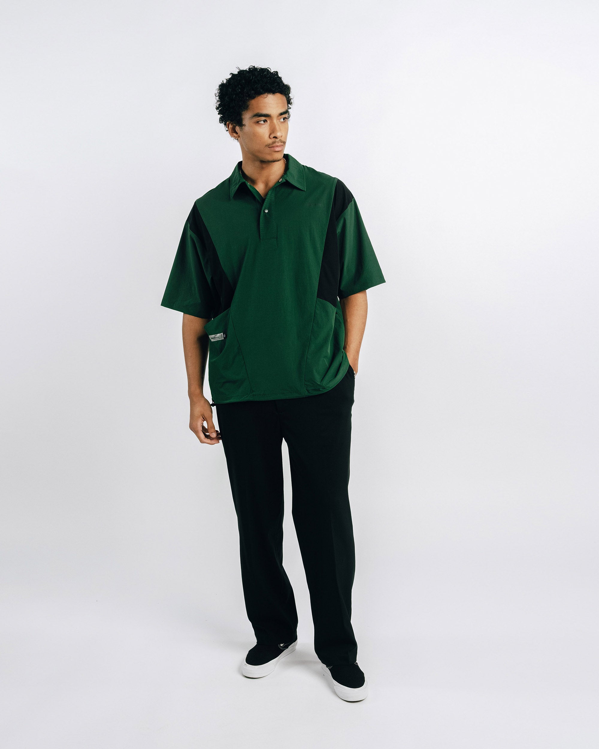 Person wearing green scrubs holding a black lanyard against a light gray background