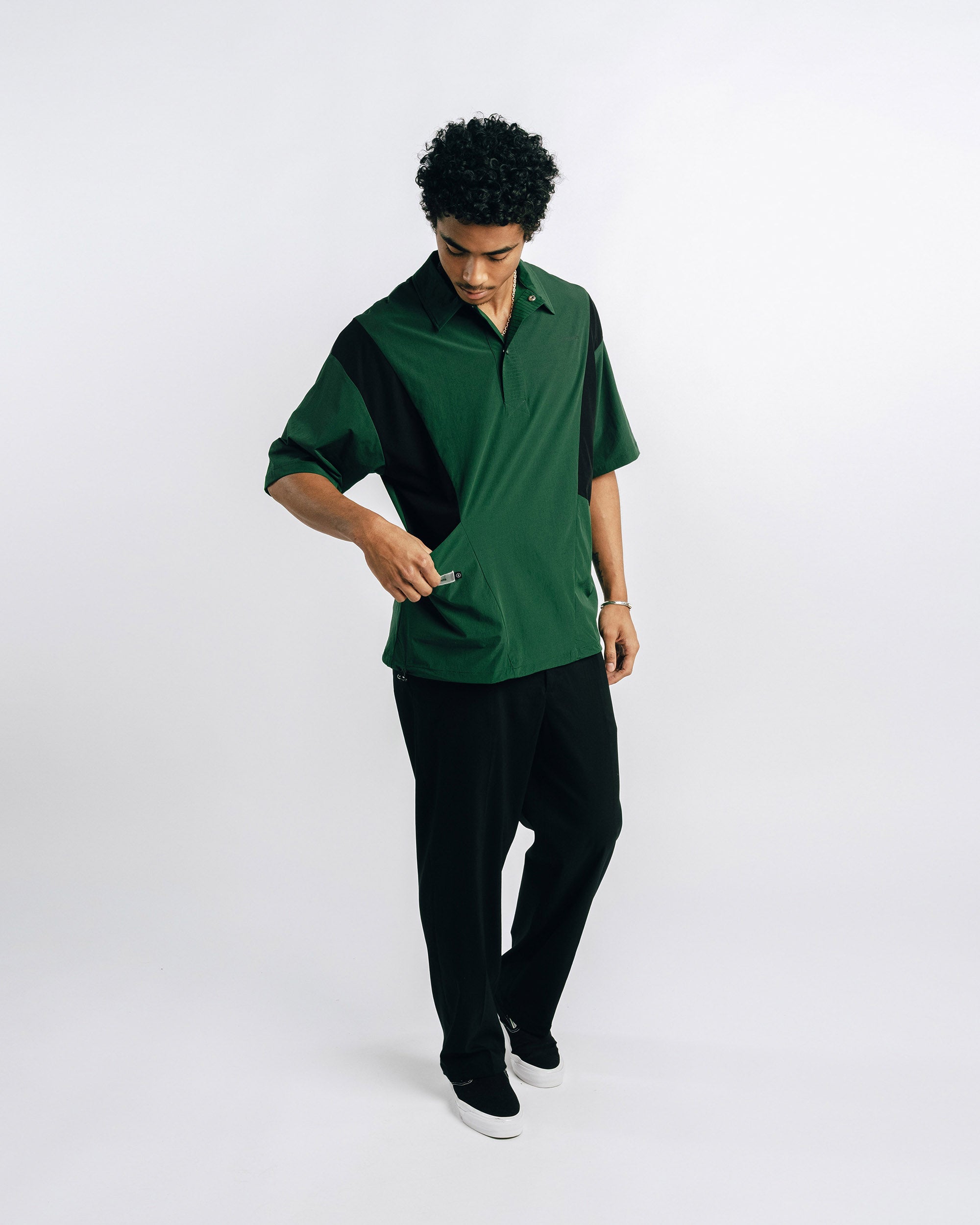 Person wearing green scrubs holding a black lanyard against a light gray background