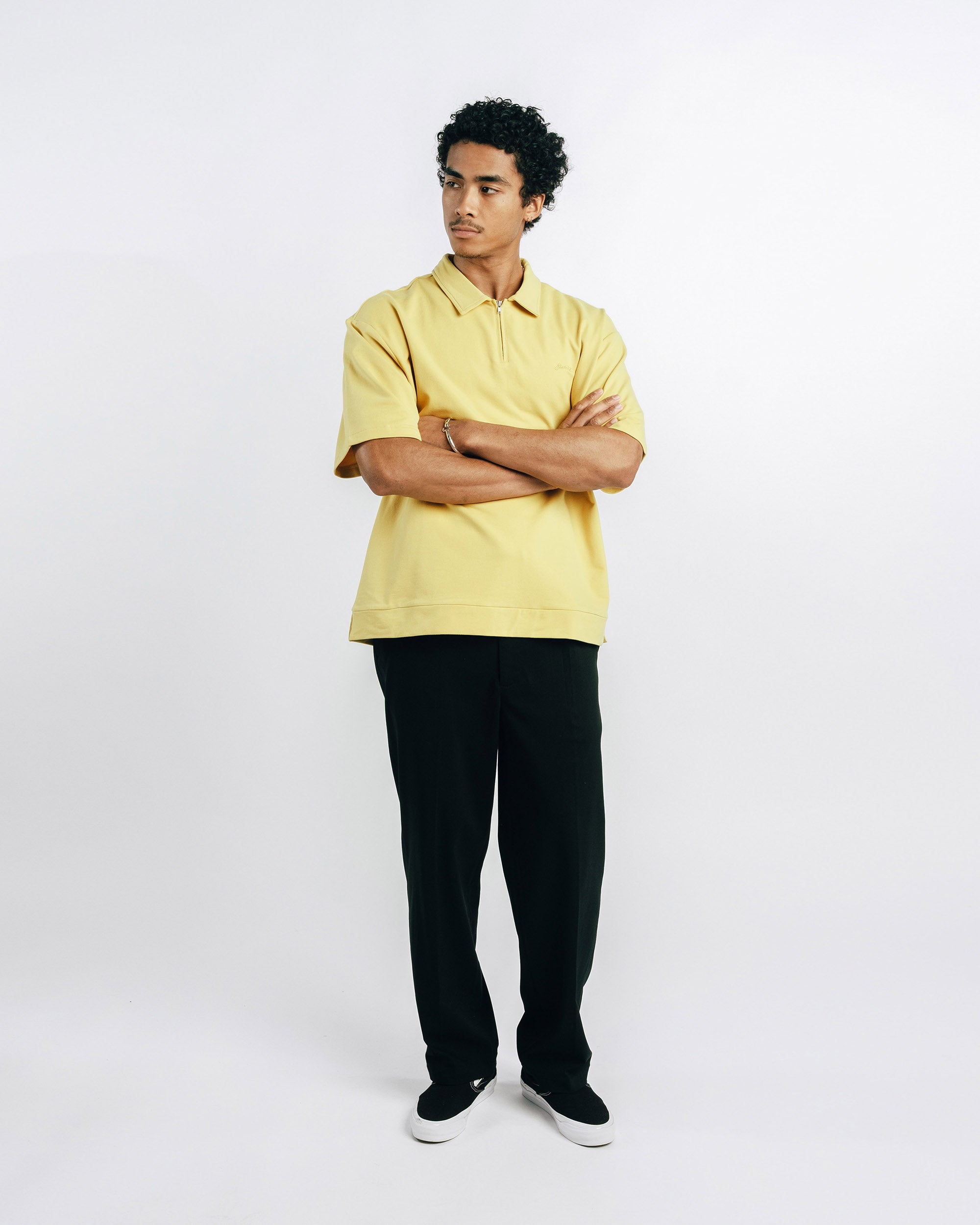 Person wearing a yellow polo shirt and black pants on a white