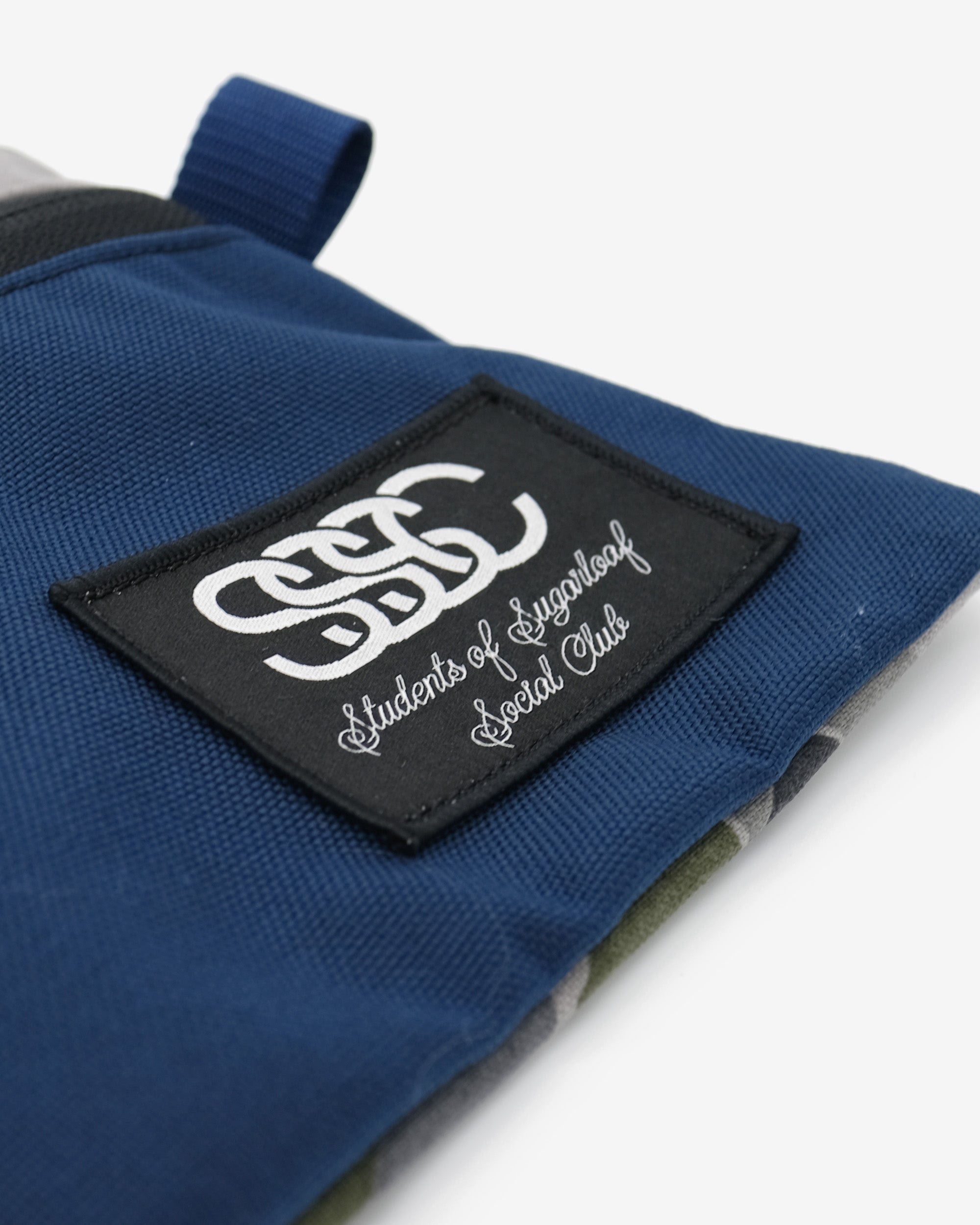 Blue glove with a black patch featuring white text on a white background