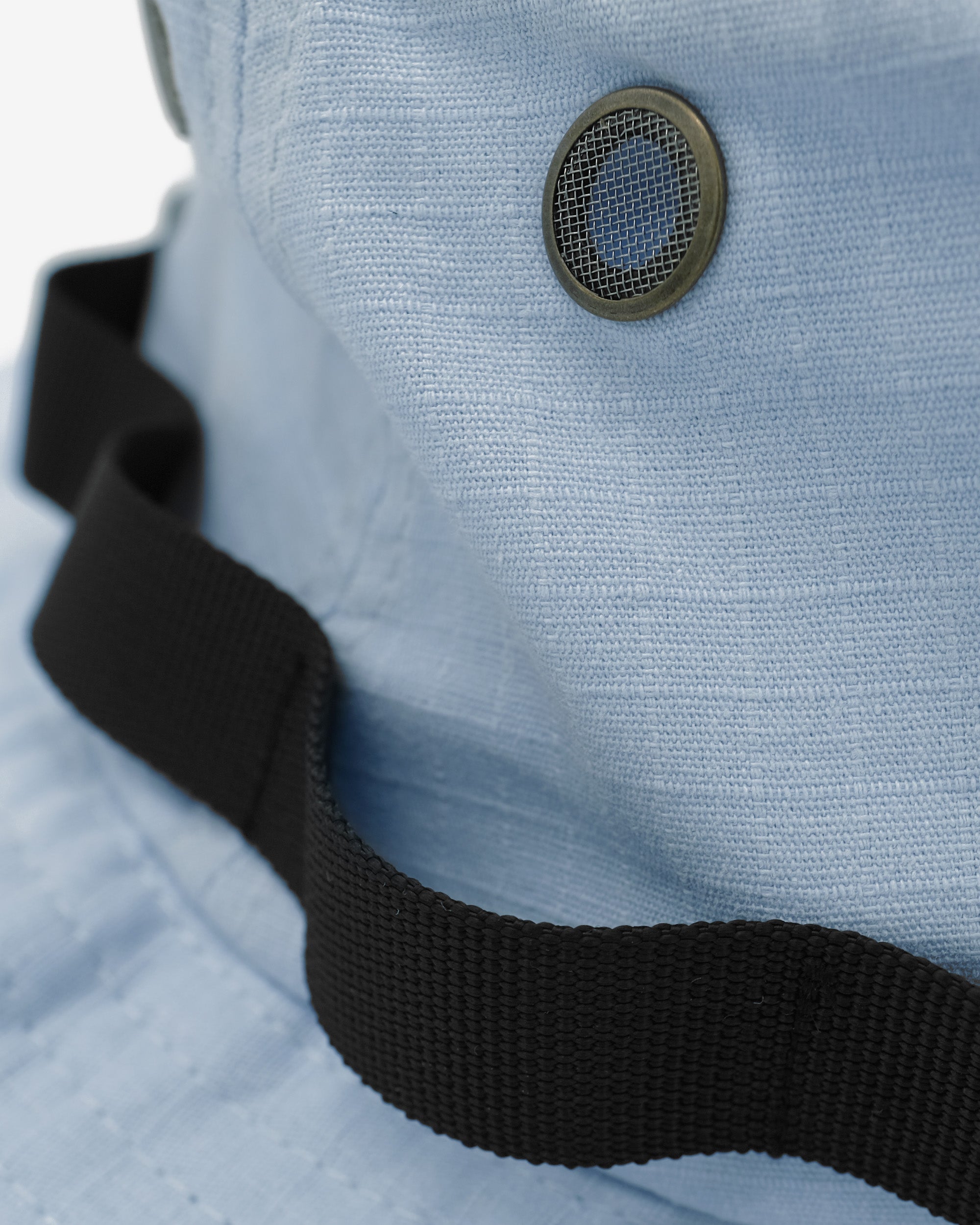 Close-up of a light blue fabric with a black strap and metal grommet.