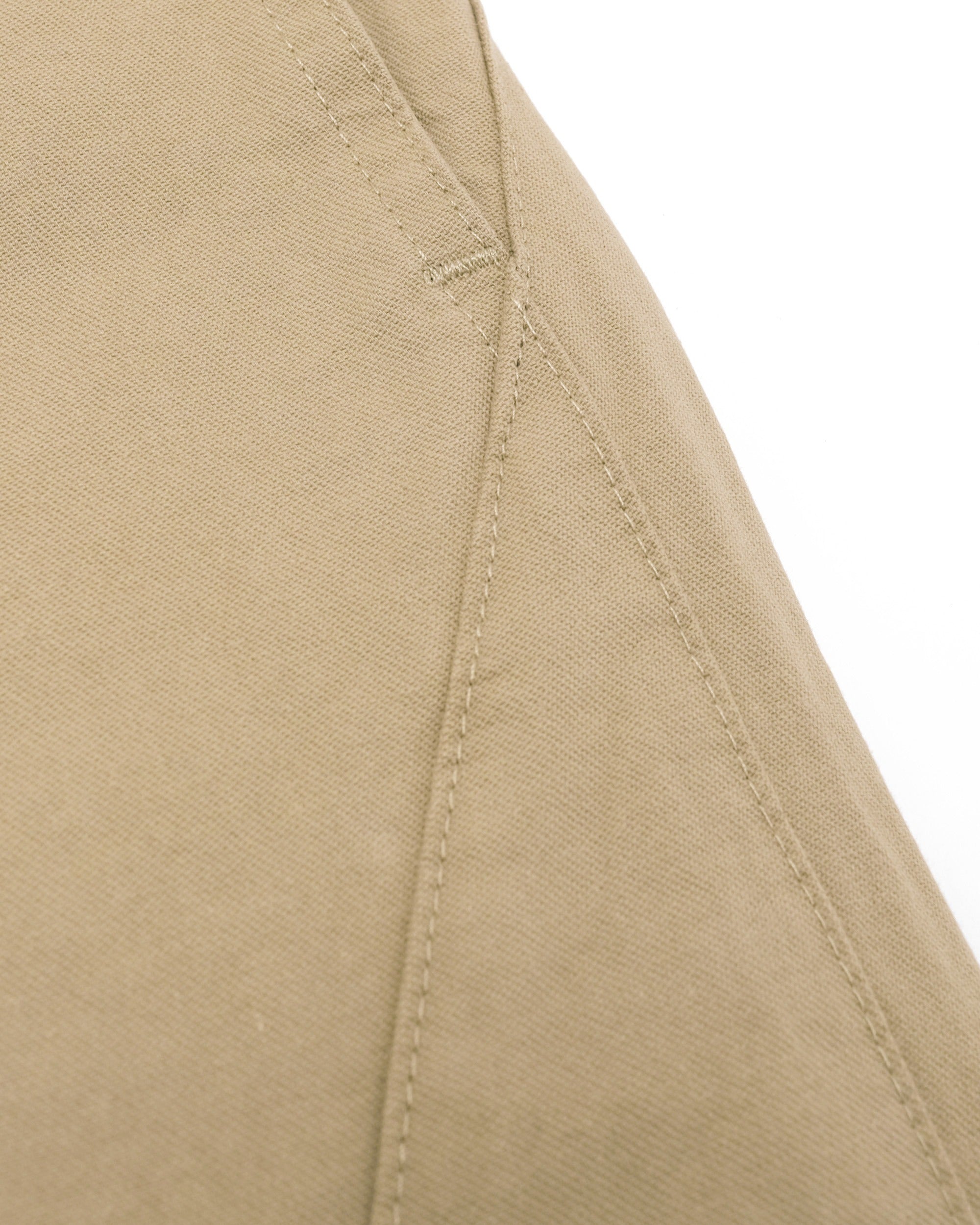 Close-up of beige fabric with stitching detail on a white background