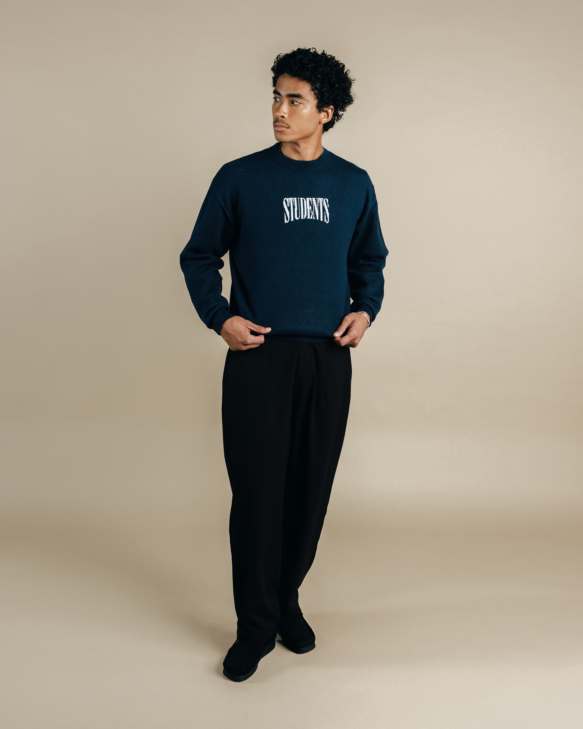 Person wearing a navy sweatshirt with 'STUDENTS' text on a beige background