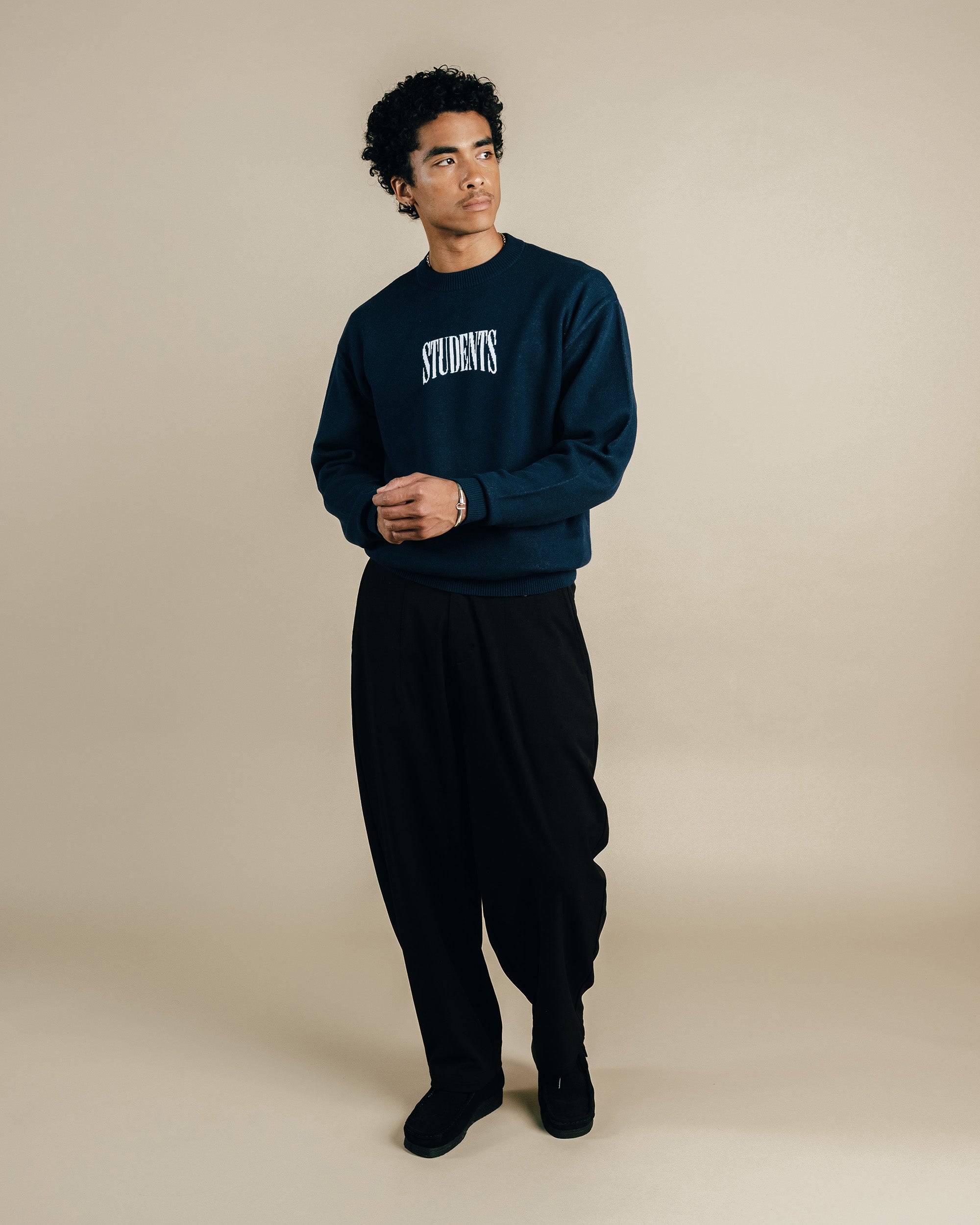 Man wearing a navy blue sweatshirt with 'STUDENTS' text on a beige background