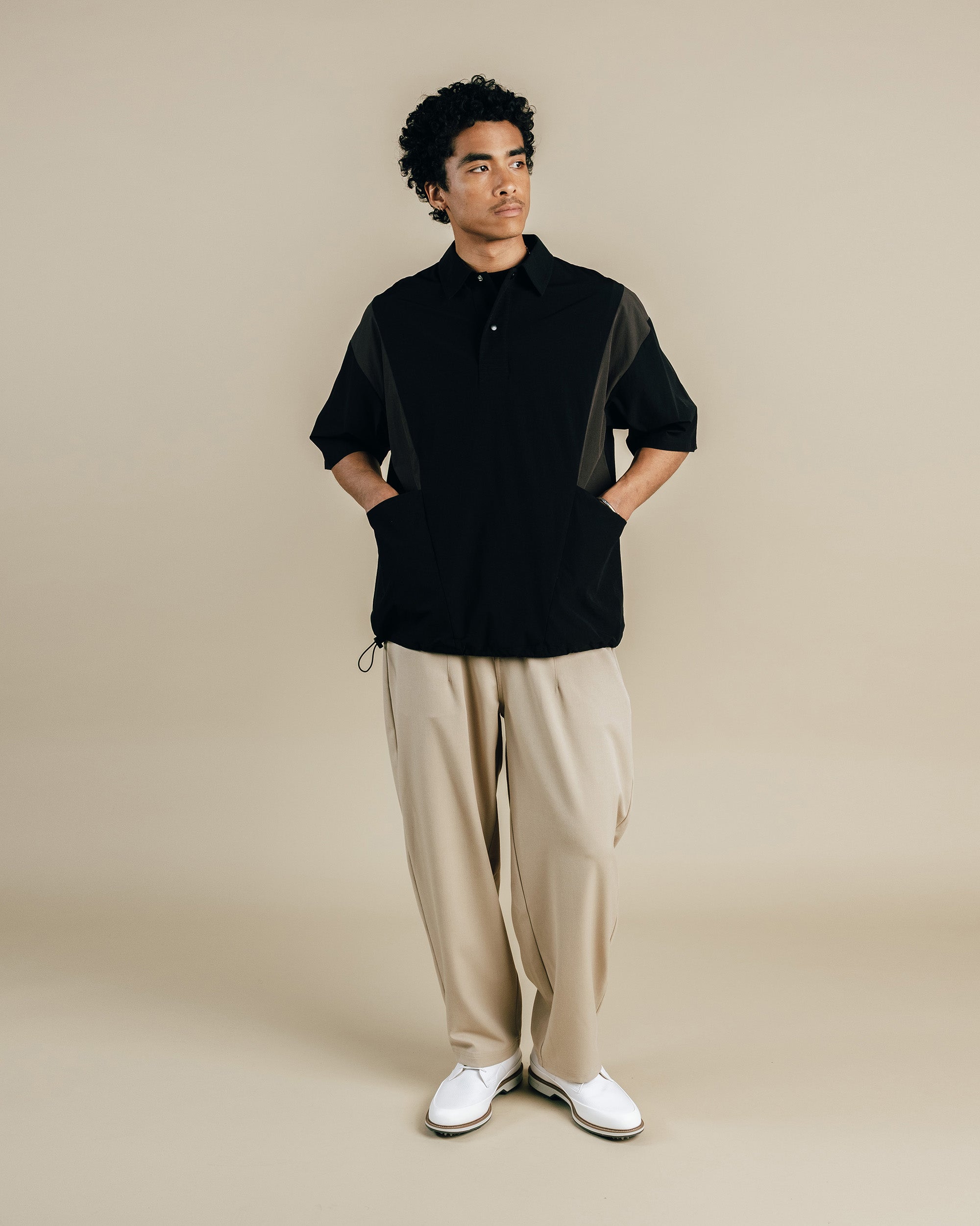 Man wearing a black shirt and beige pants on a beige background