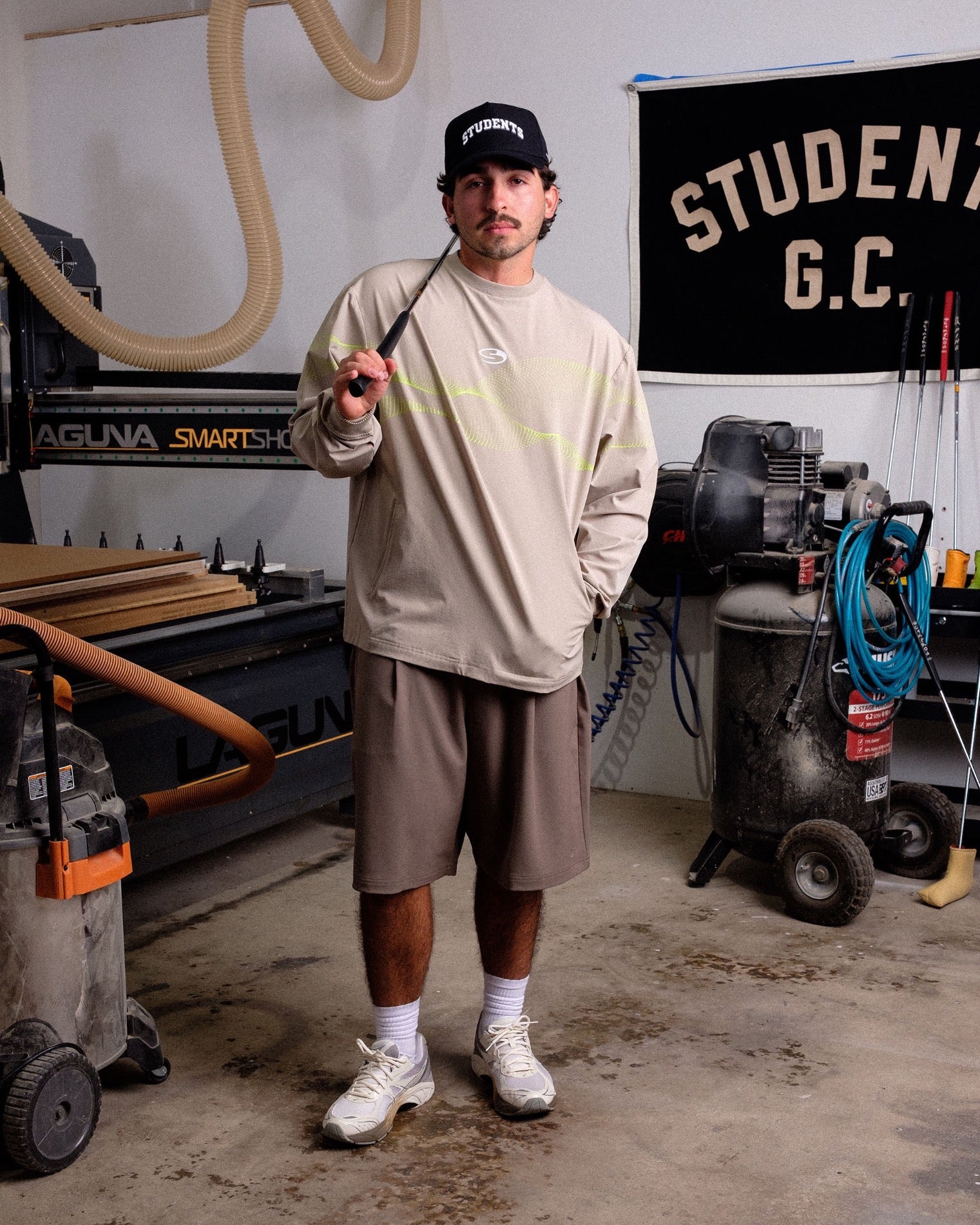 Man holding a golf club in a workshop with tools and equipment in the background
