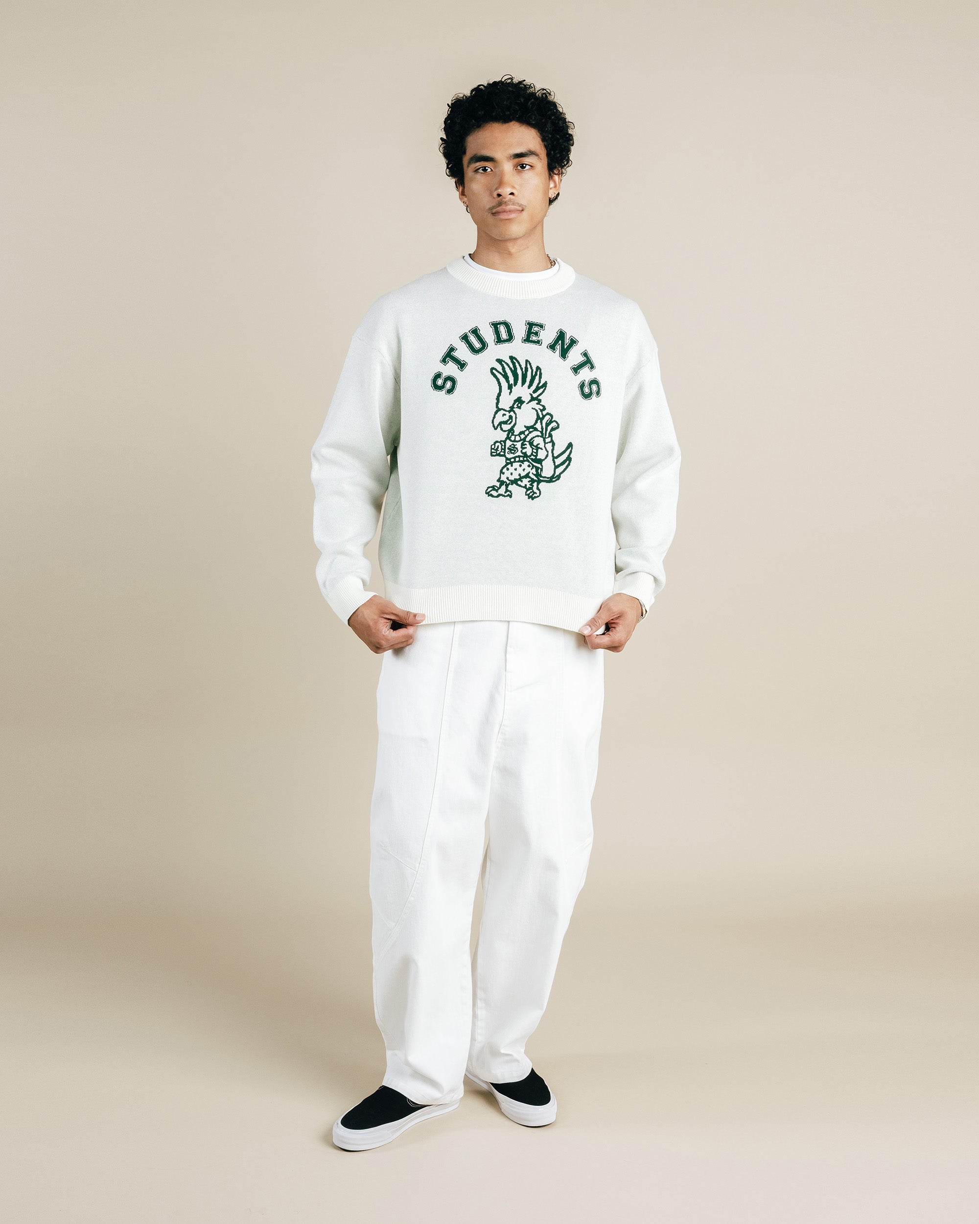 Person wearing a white sweatshirt with text and graphics, standing against a plain background