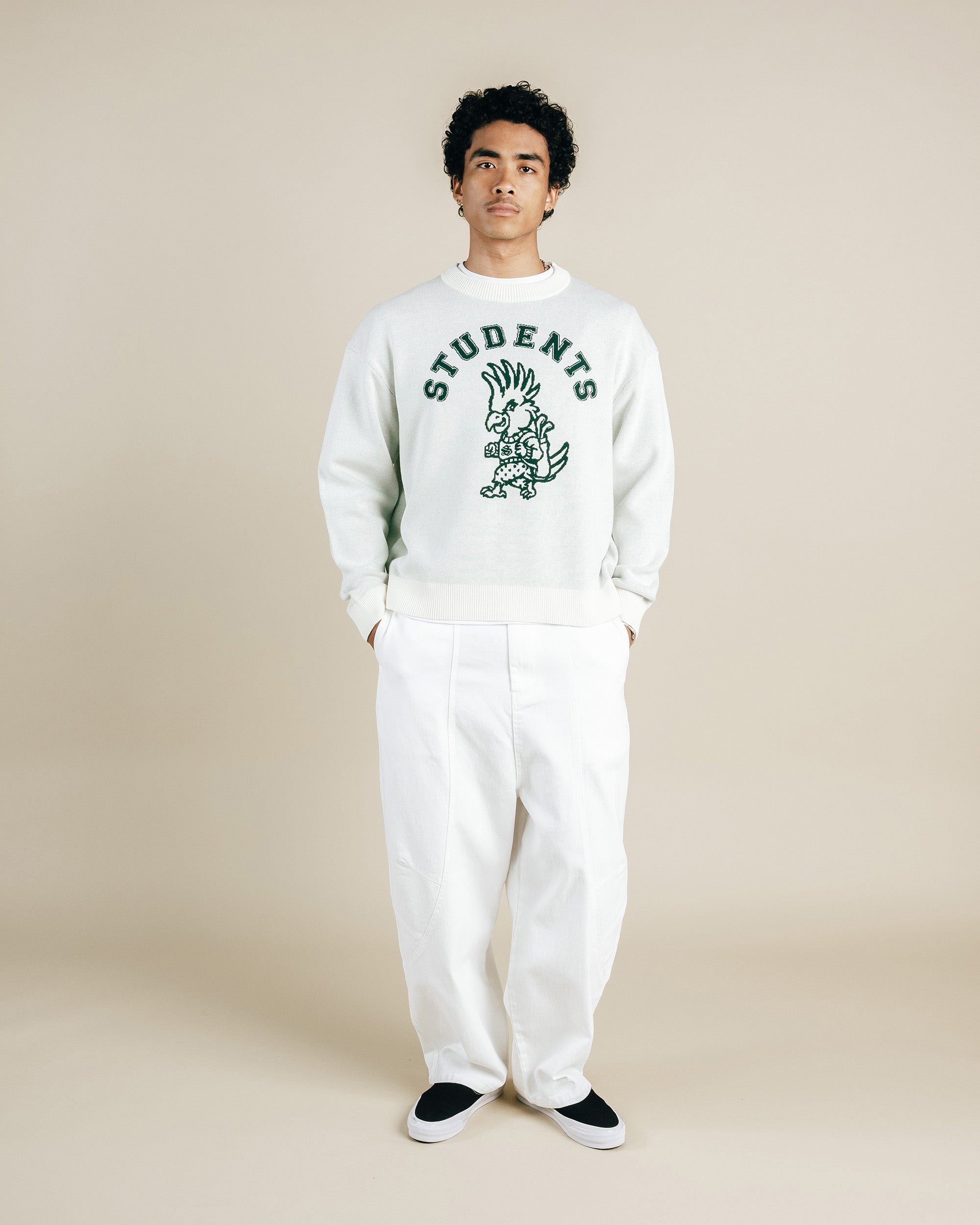 Person wearing a white sweatshirt with a graphic design and text, standing against a plain background