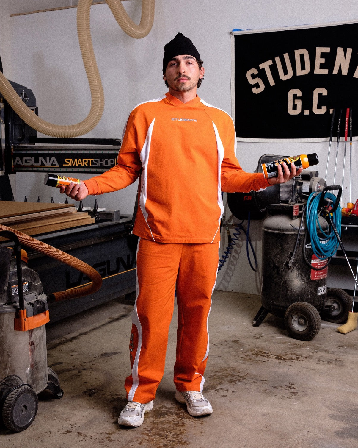 Person wearing an orange jumpsuit with white stripes in a workshop setting