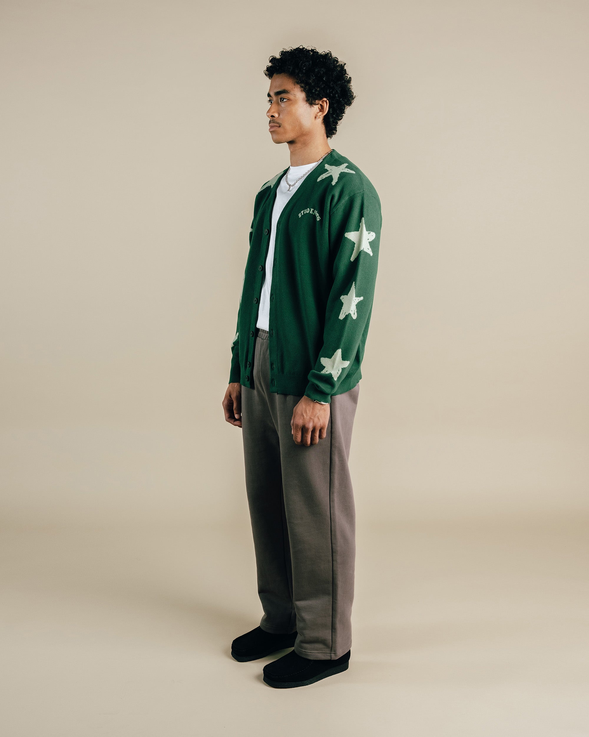 Person wearing a green cardigan with star patterns on a beige background