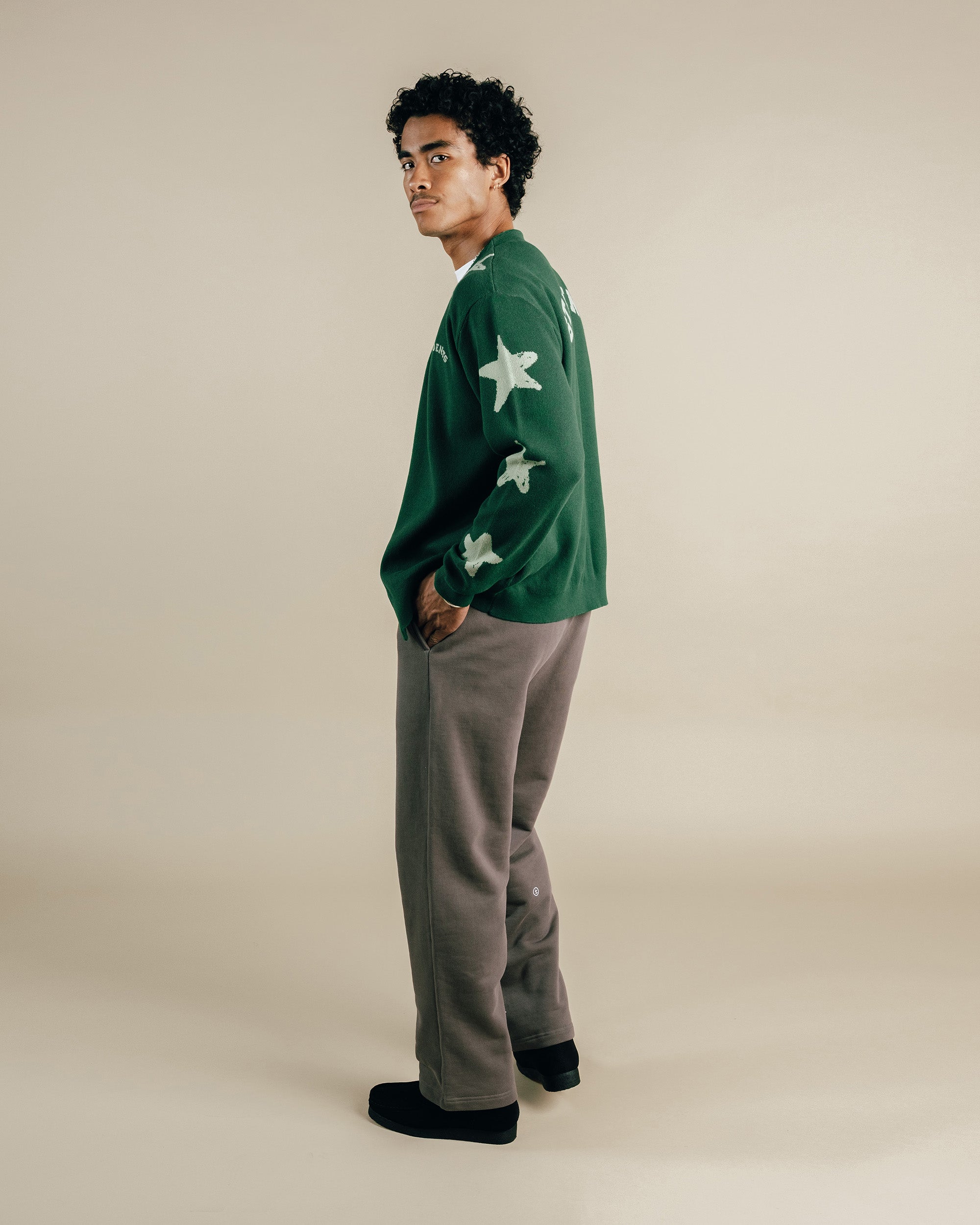Person wearing a green sweater with white star patterns on a beige background