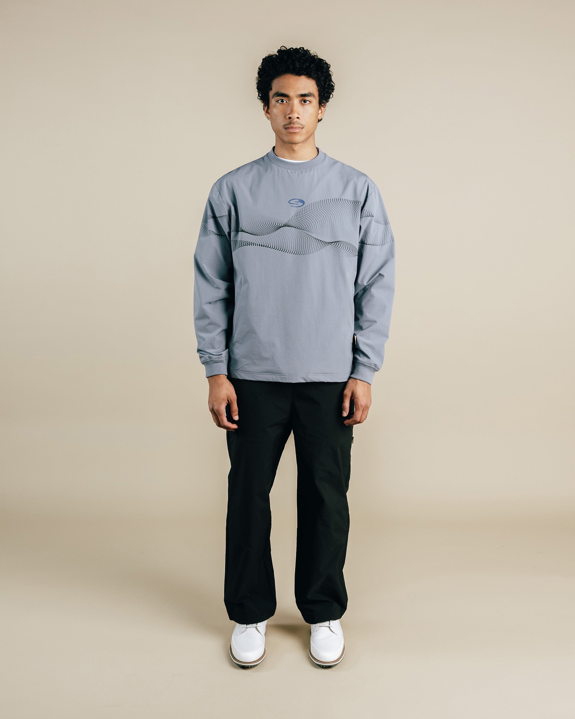 Person wearing a gray sweatshirt and black pants on a beige background