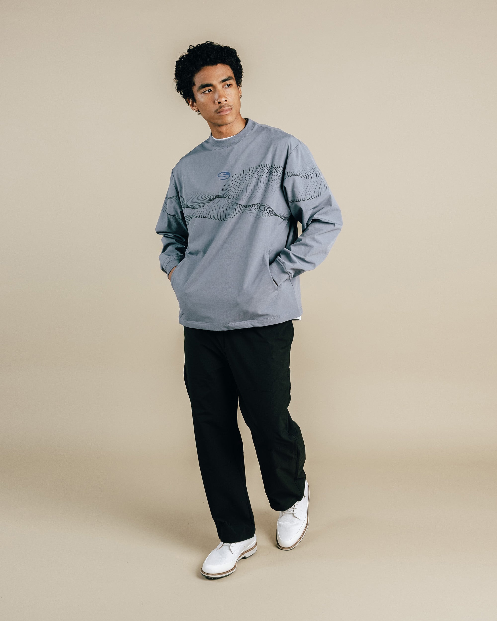 Person wearing a light gray sweatshirt and black pants on a beige background