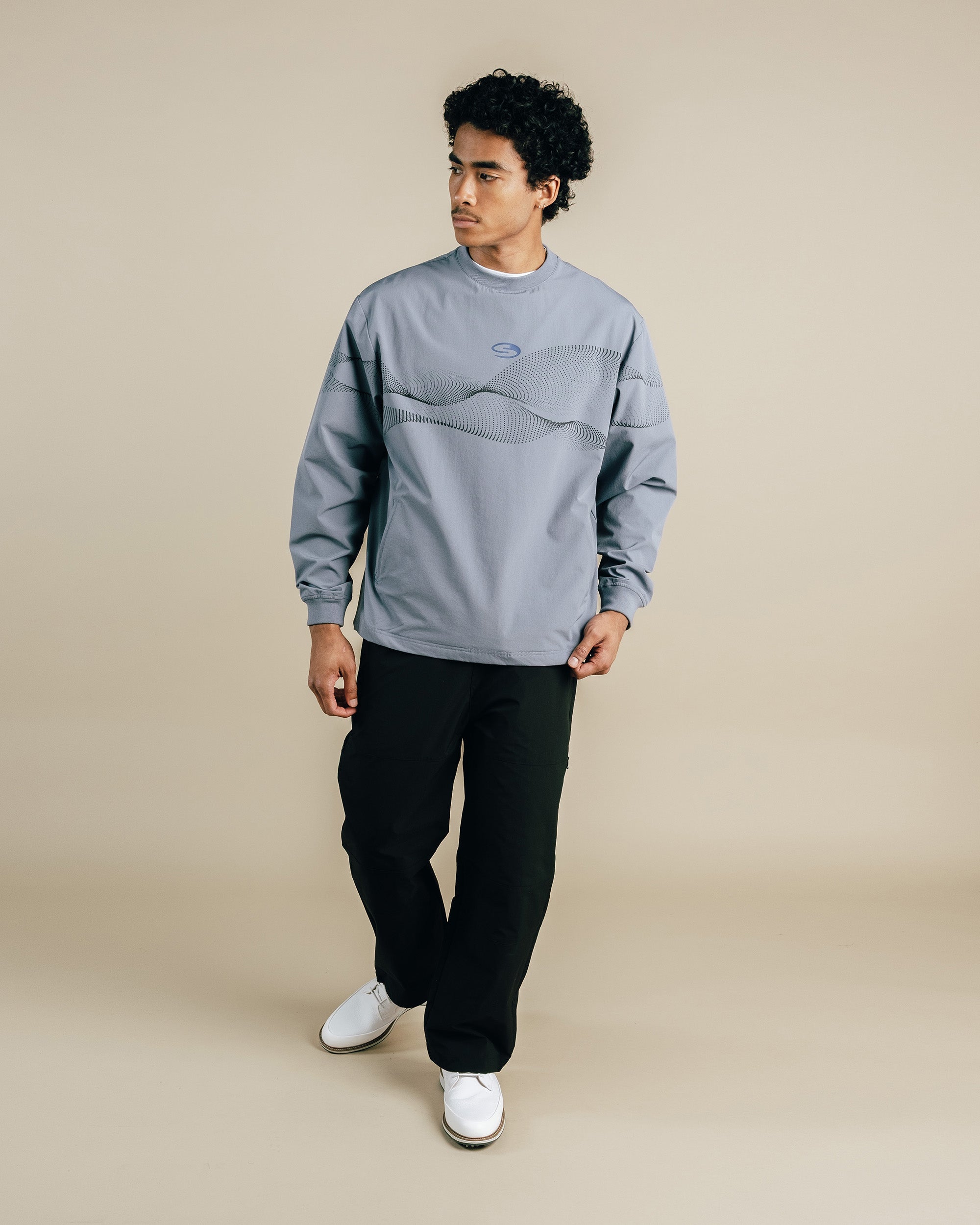 Person wearing a gray sweatshirt and black pants on a beige background