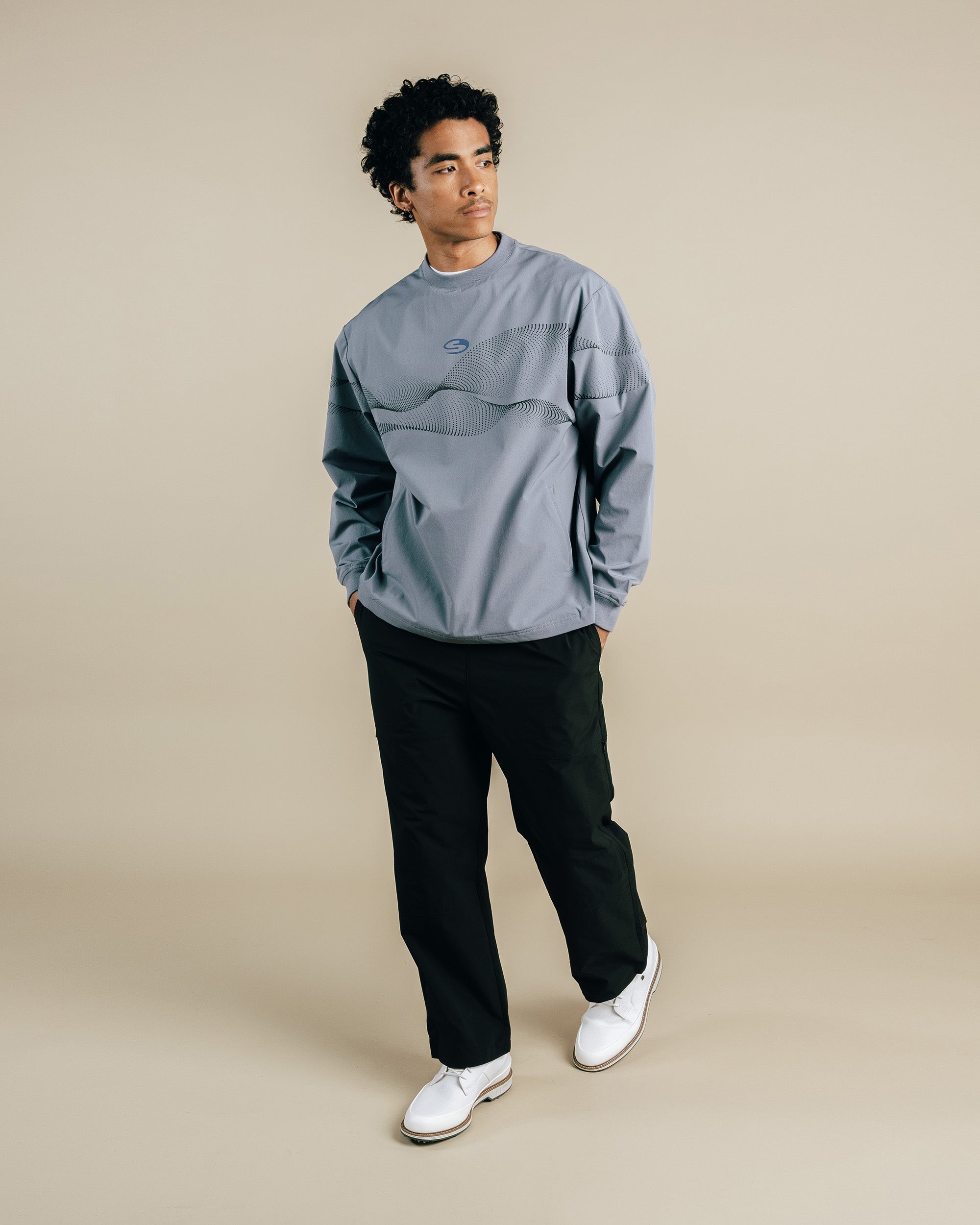 Person wearing a grey sweatshirt and black pants on a beige background