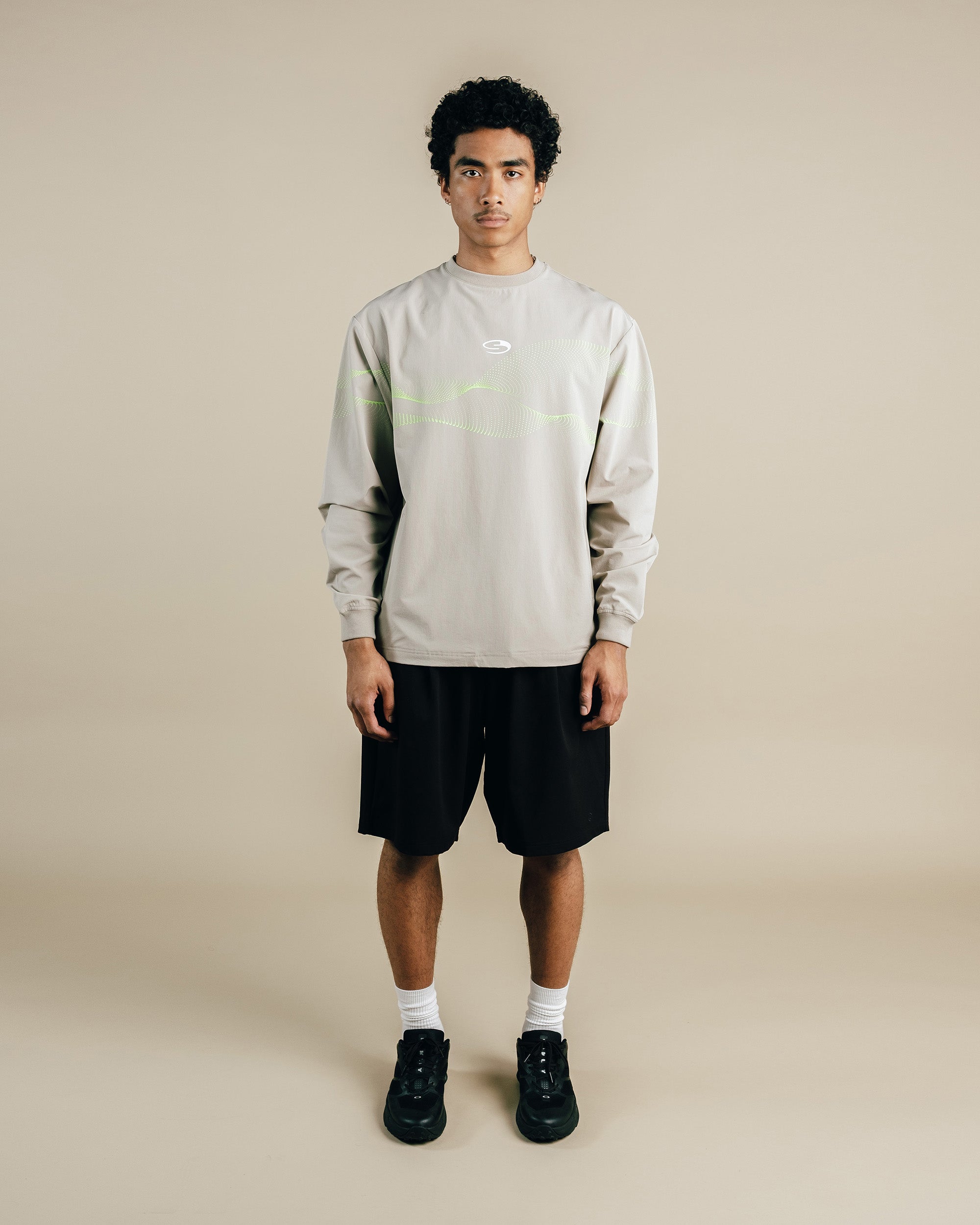 Person wearing a light gray sweatshirt and black shorts on a beige background