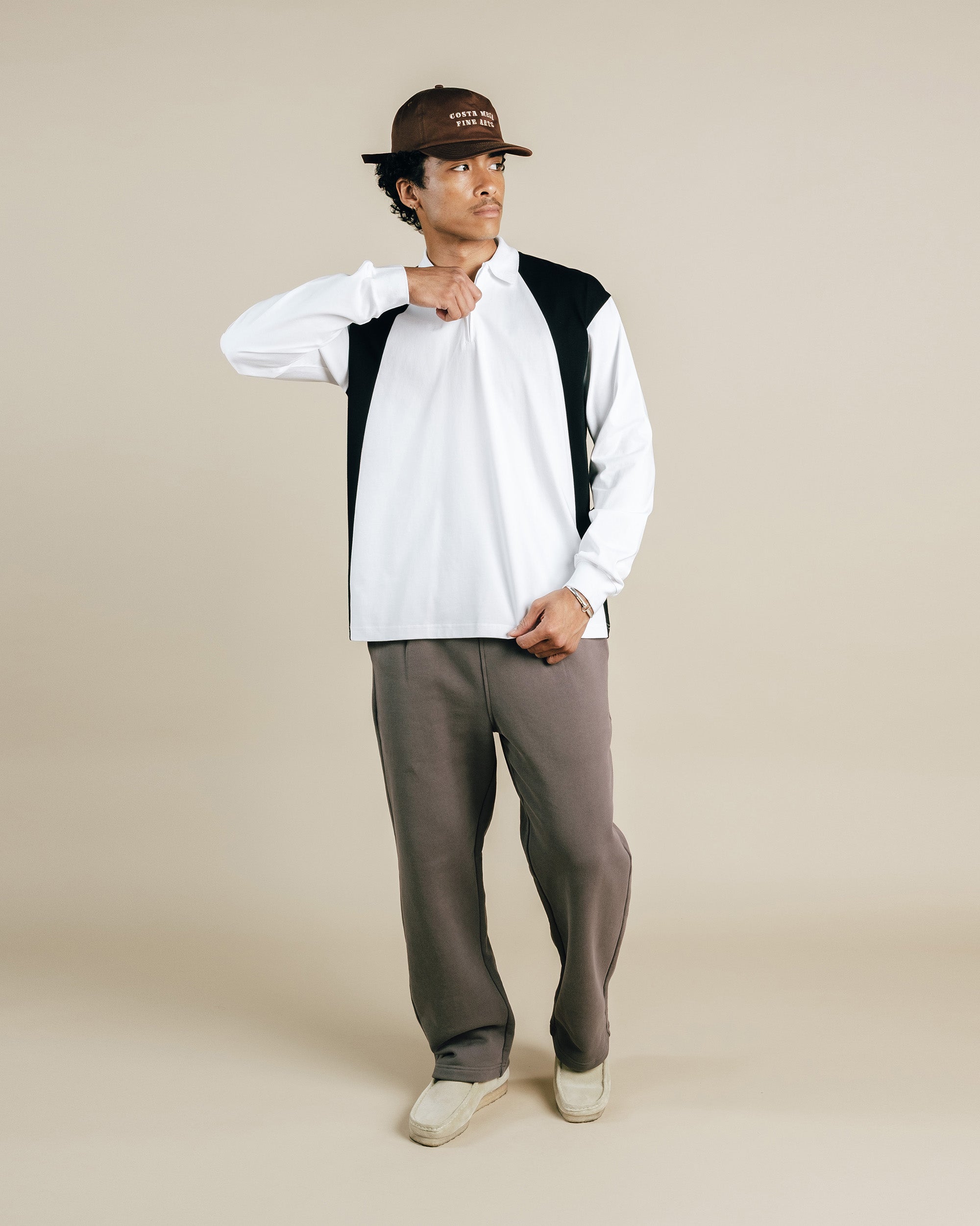 Person wearing a white and black long-sleeve shirt with gray pants on a beige background