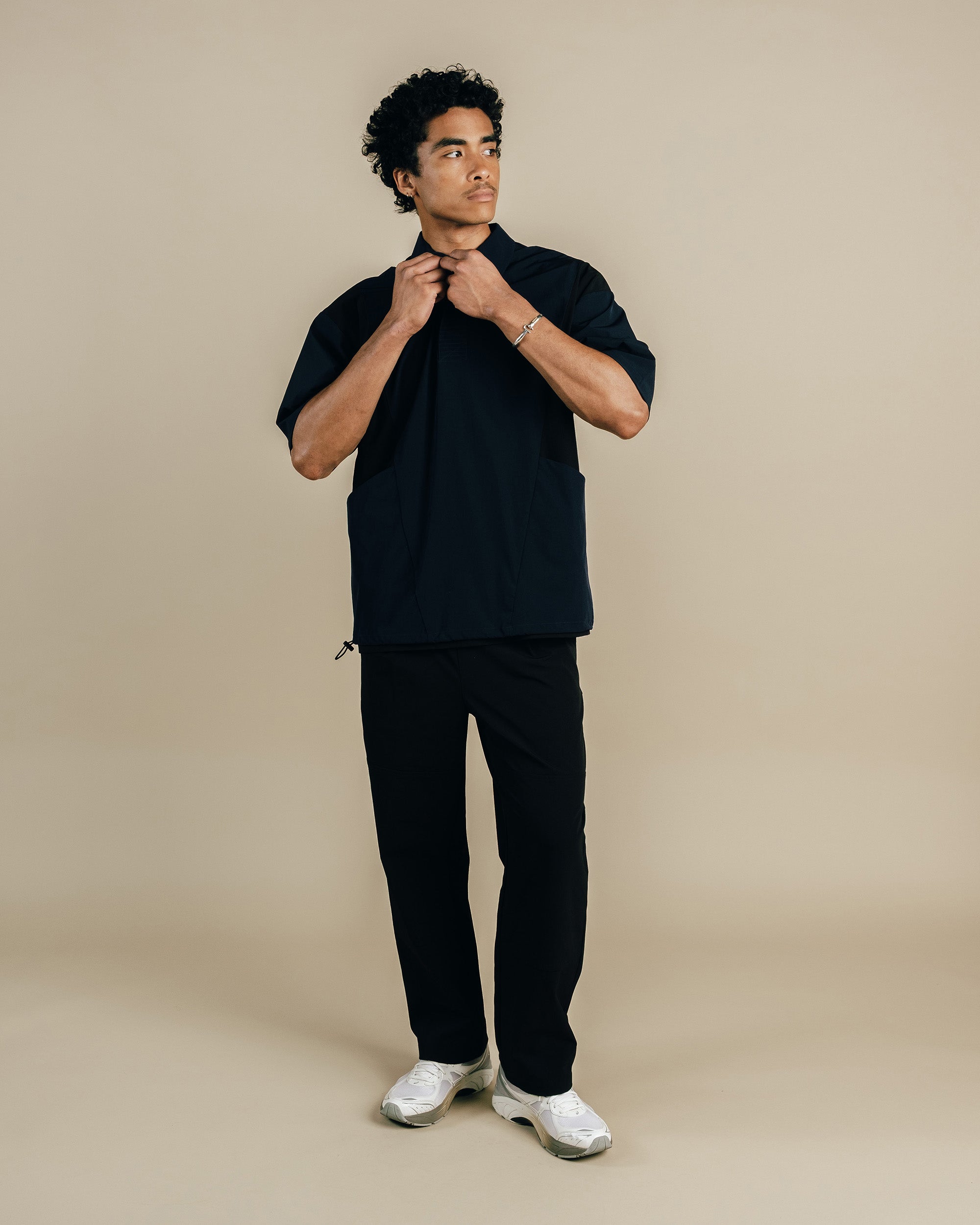 Man wearing a black outfit on a beige background