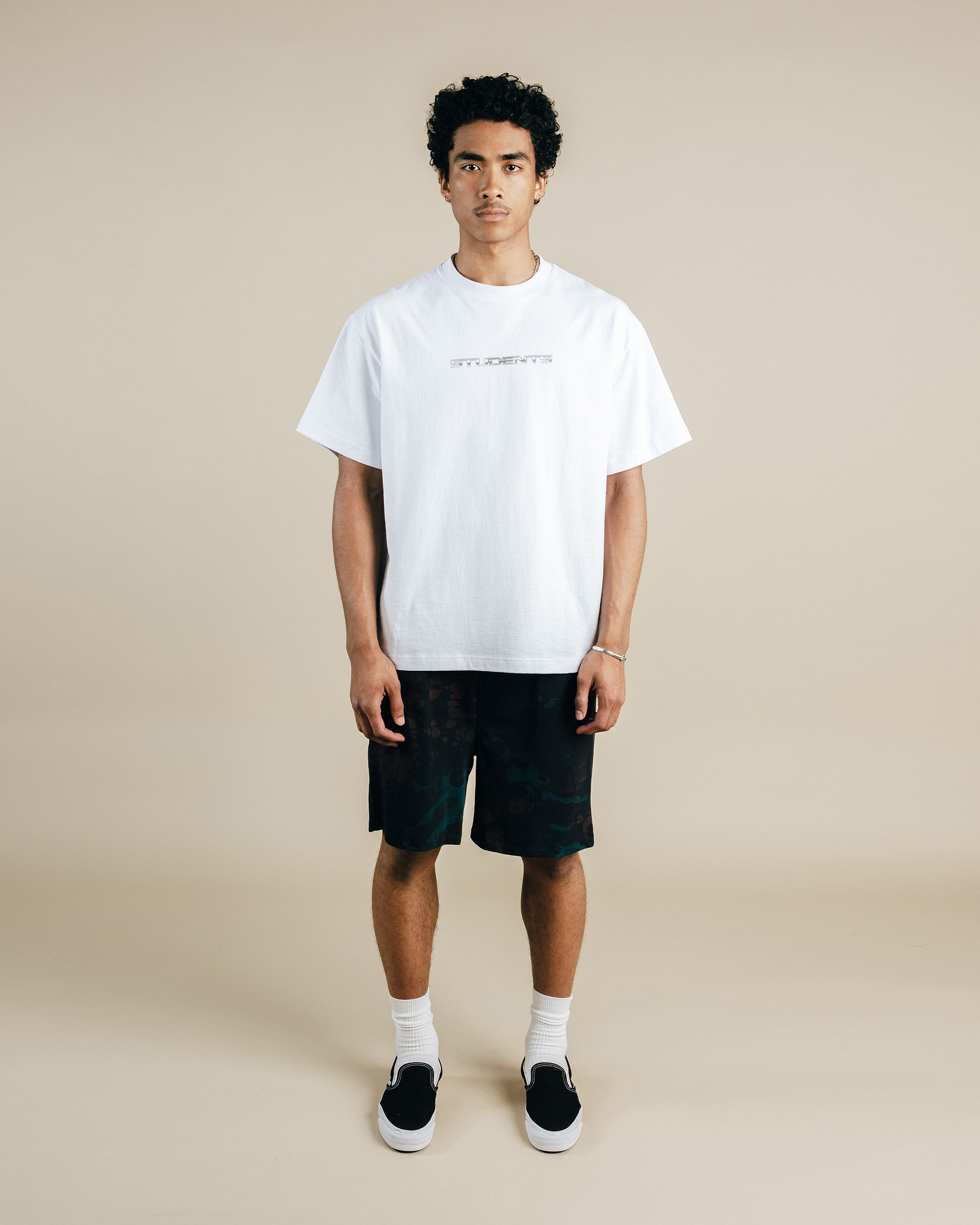 Person wearing a white t-shirt and black shorts on a beige background