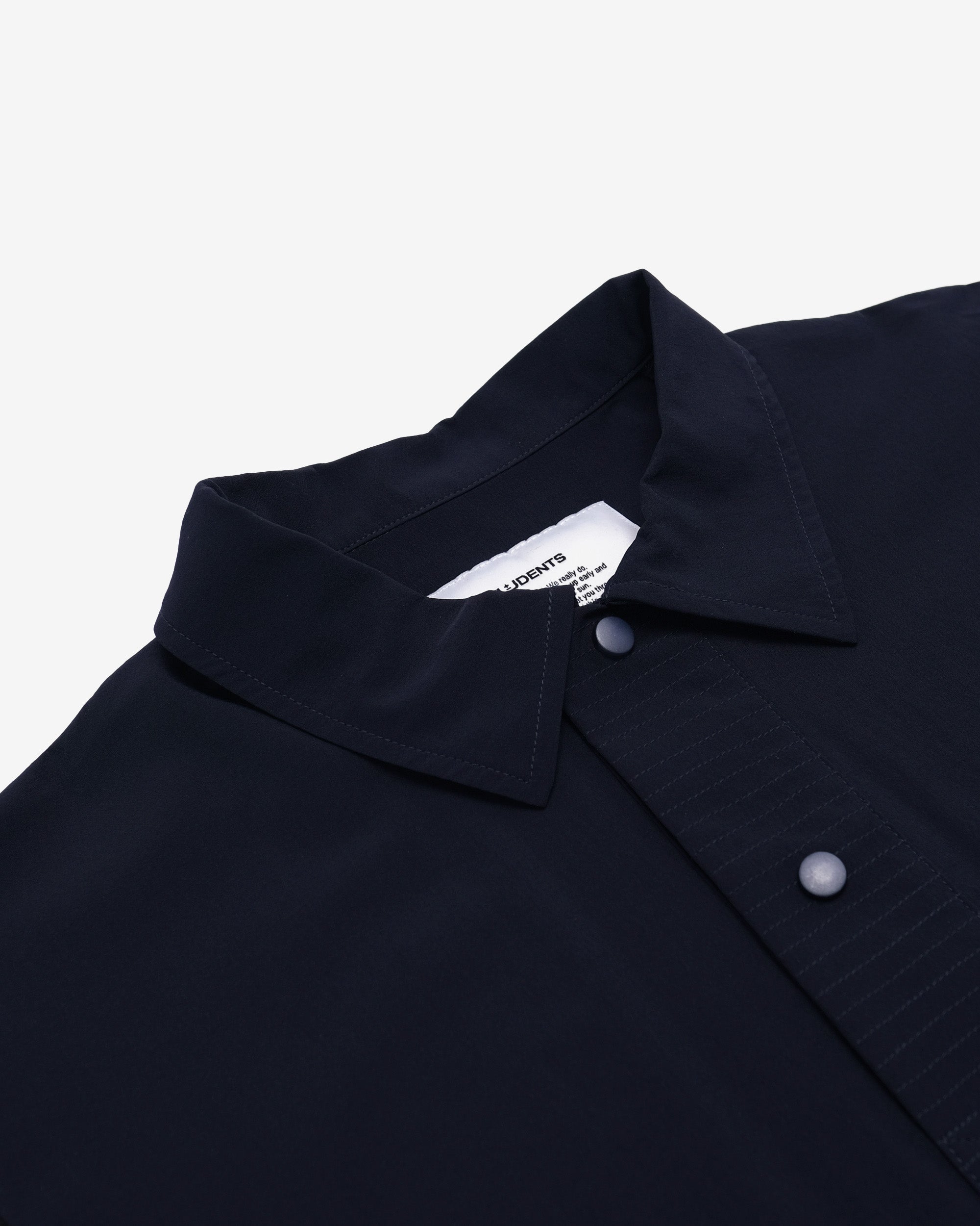Close-up of a dark blue shirt collar with buttons on a light gray background