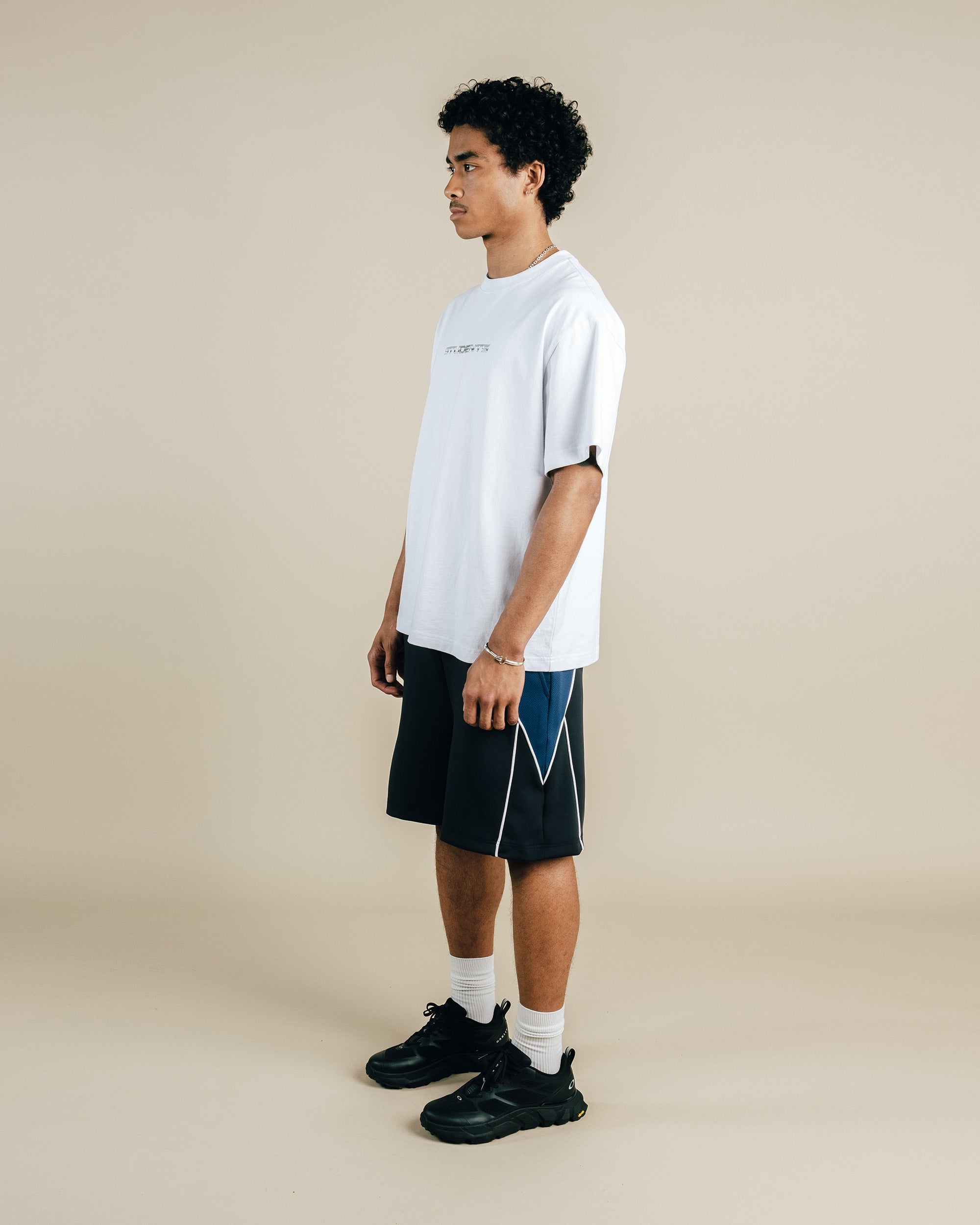 Person wearing a white t-shirt and black shorts on a beige background